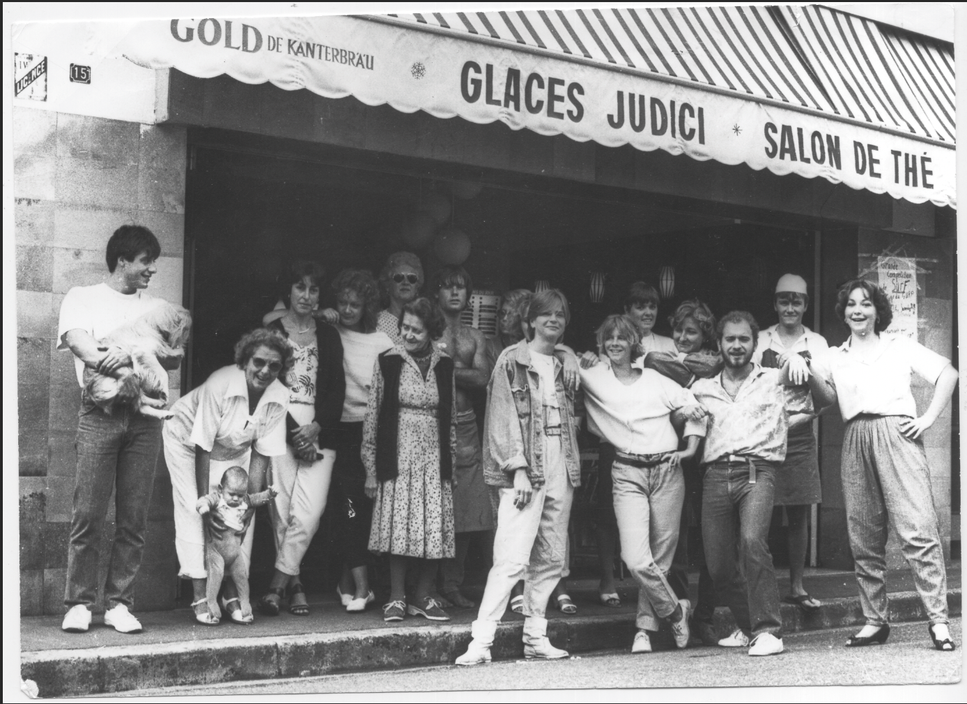 Groupe de personnes posant devant une boutique avec une enseigne indiquant 'Glaces Judici'.