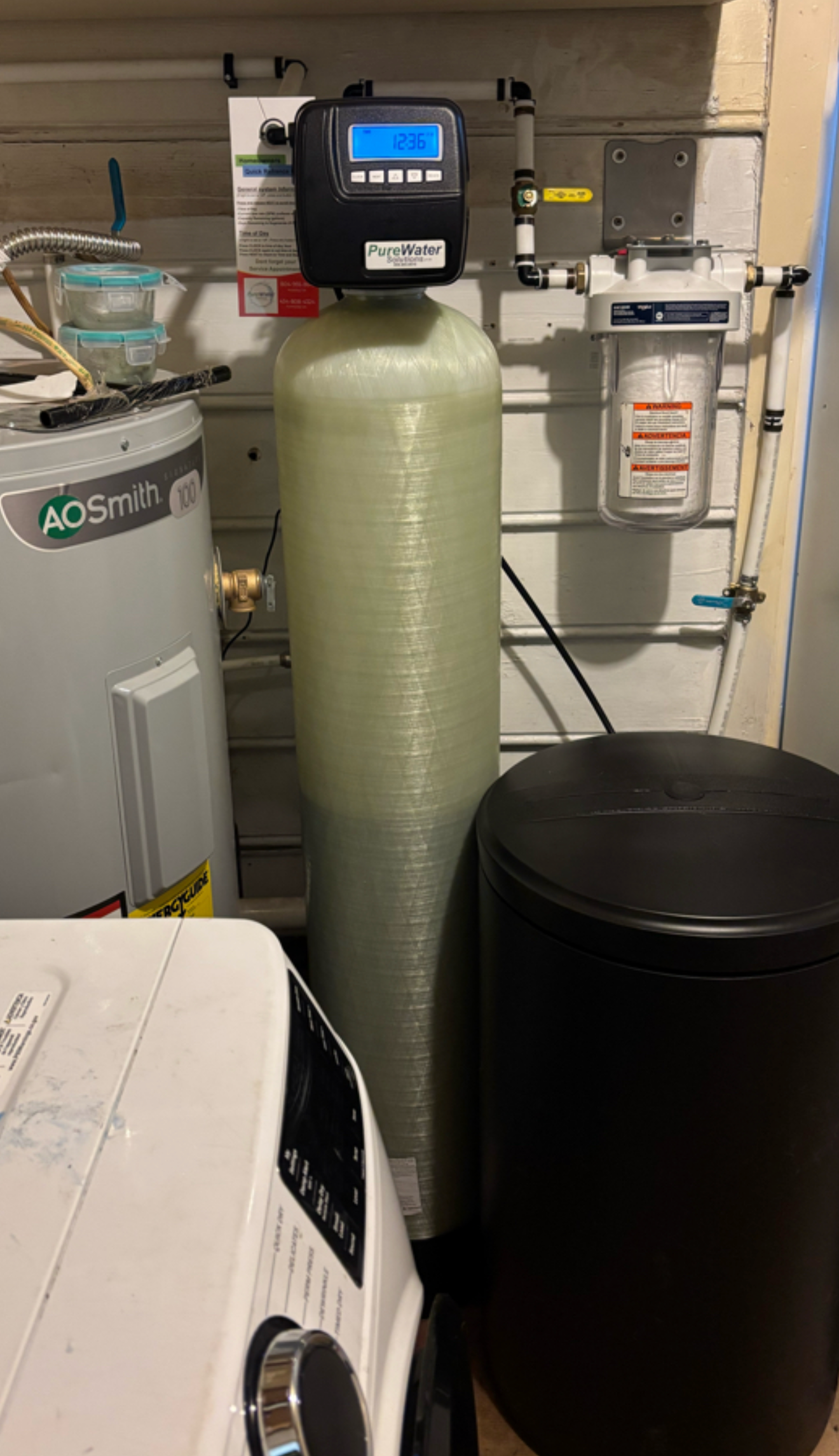 A water softener, water heater, and laundry machine in a utility room.