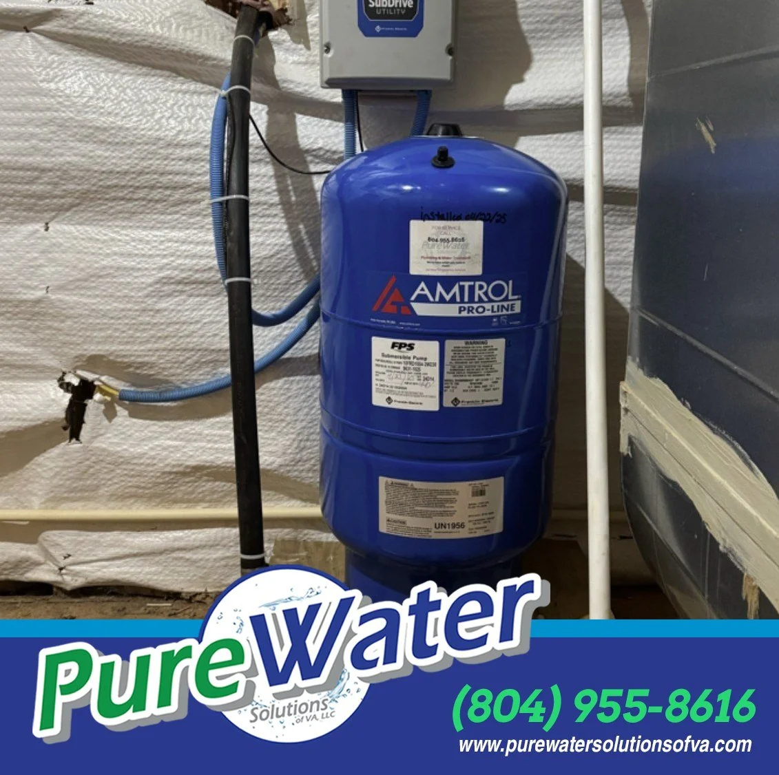 A blue Amtral Pro-Line water filtration tank mounted on a wall in a utility room, with pipes and electrical boxes nearby, and a promotional overlay at the bottom with the text "Pure Water Solutions" and contact information.
