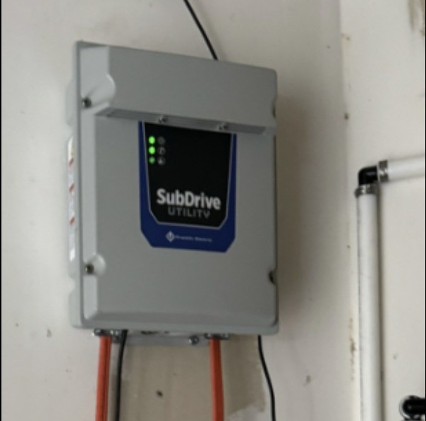Electrical subdrive utility box mounted on a wall with indicator lights, connected to orange and black cables.