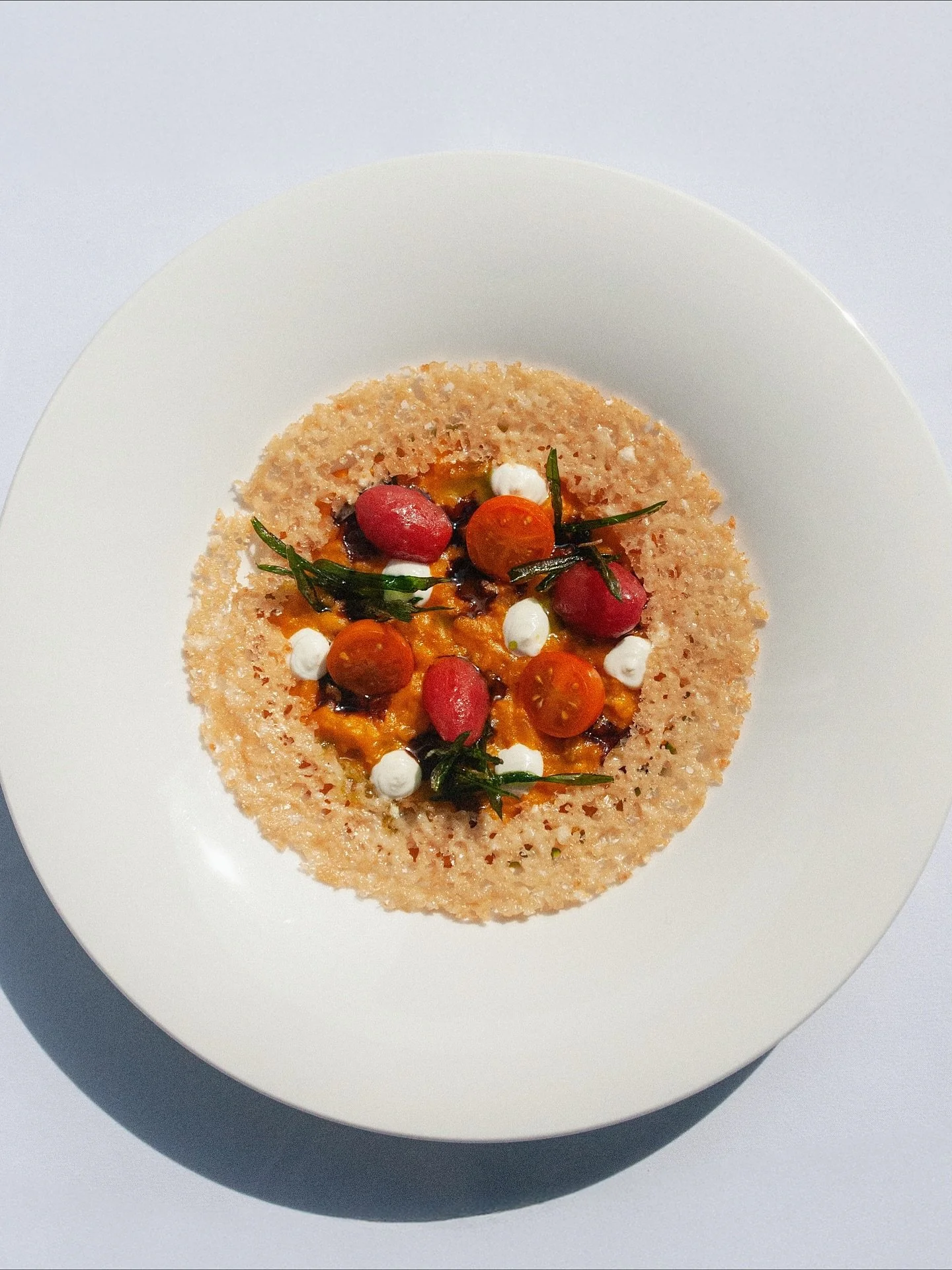 Meet our Tomato Risotto: Amana orange tomatoes, goat cheese mousse, Modena balsamic, and a hint of tarragon under a parmesan crown.