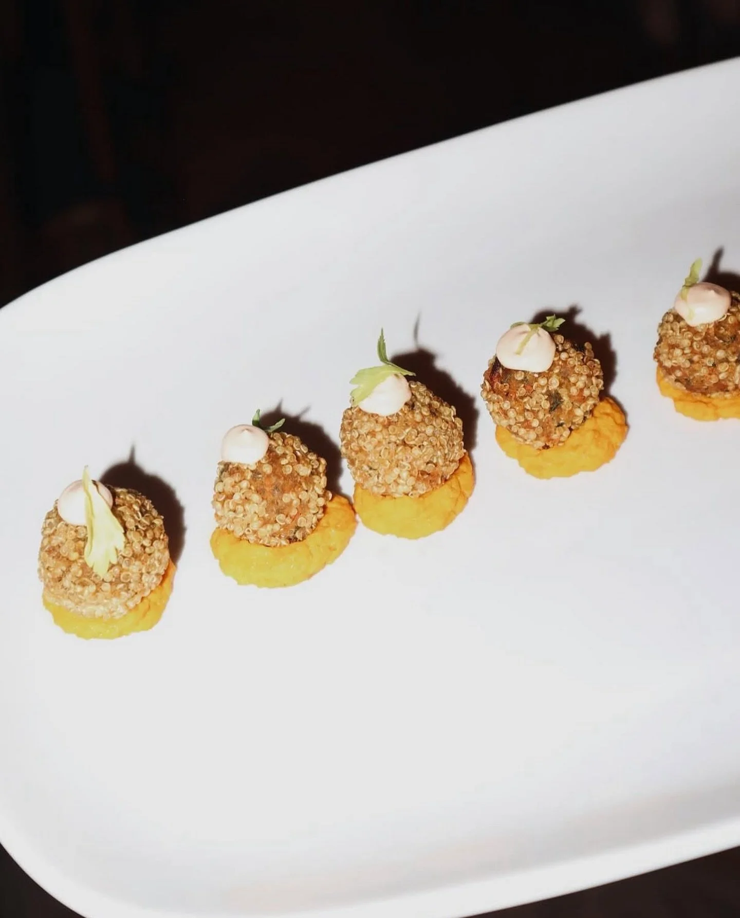 Quinoa-crusted carrot falafel, served with carrot hummus and harissa crema.