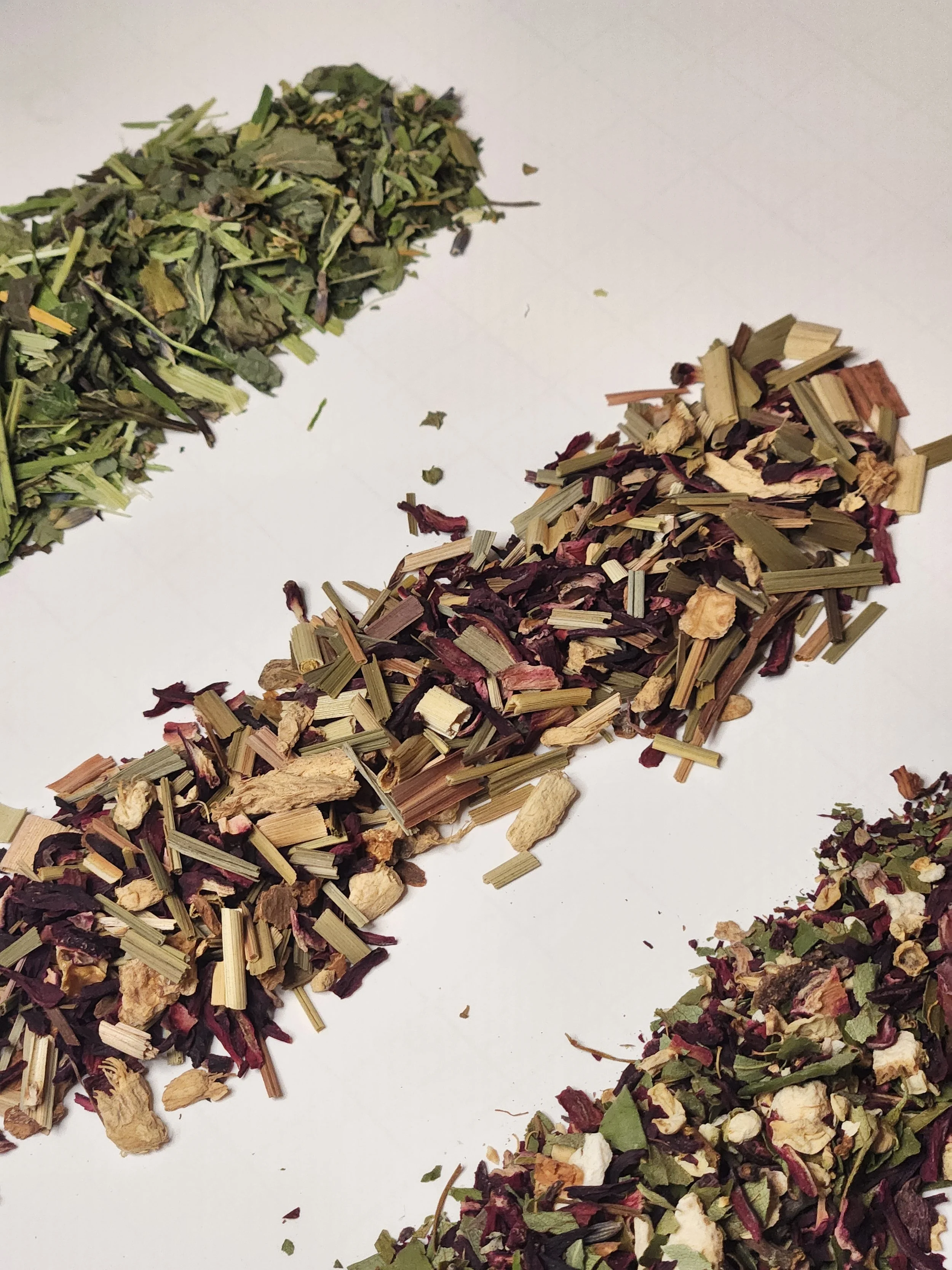 Three small piles of loose leaf herbal teas
