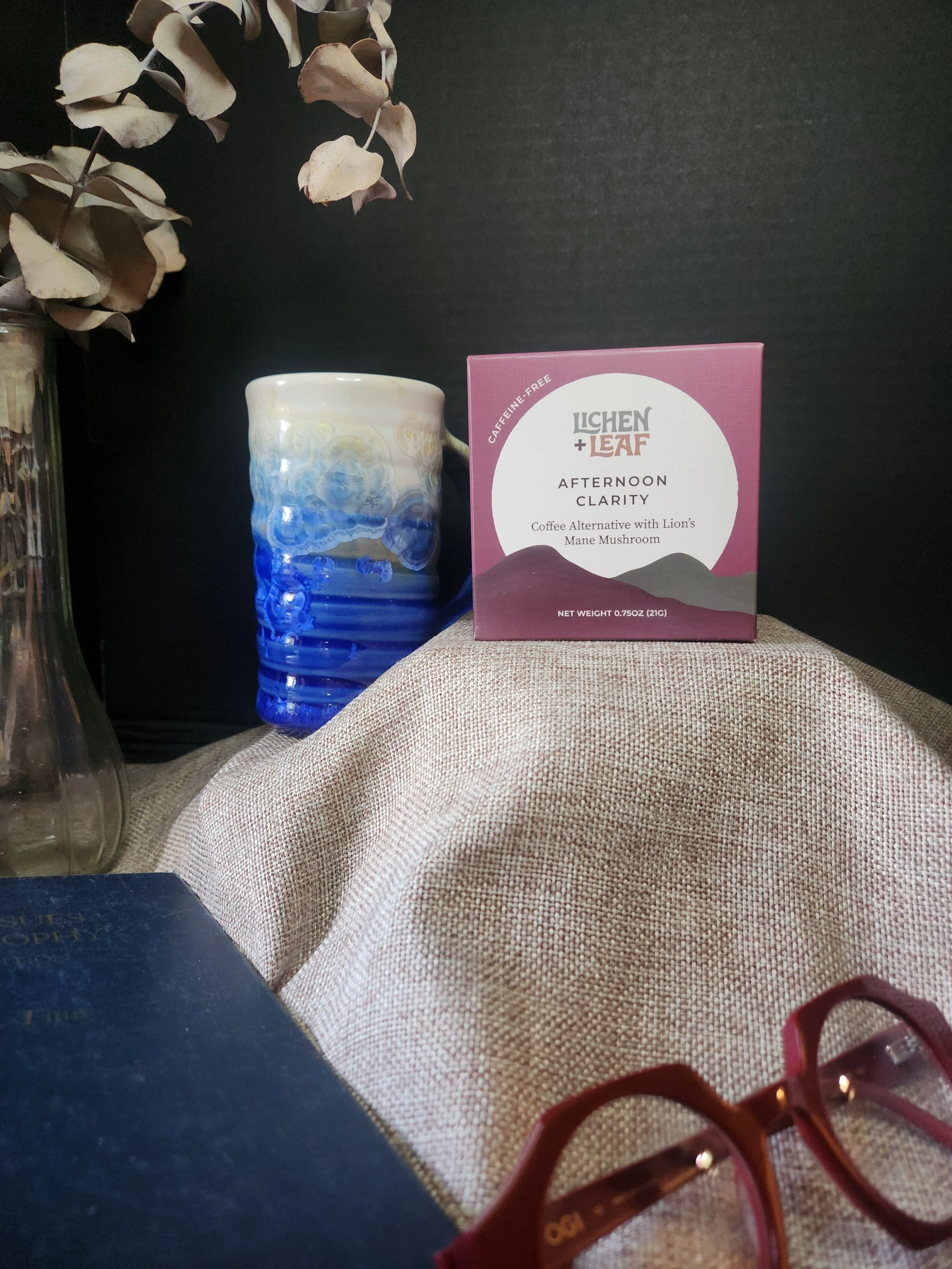 A picture of a mug of tea with a box saying "Afternoon Clarity" a book and a  pair of glasses