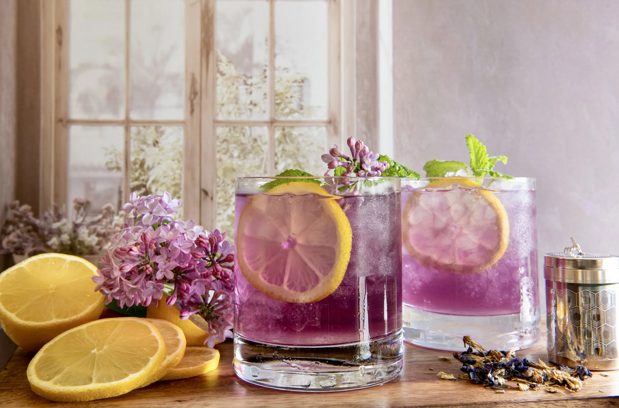 Glass mug filled with purple herbal tea and flowers