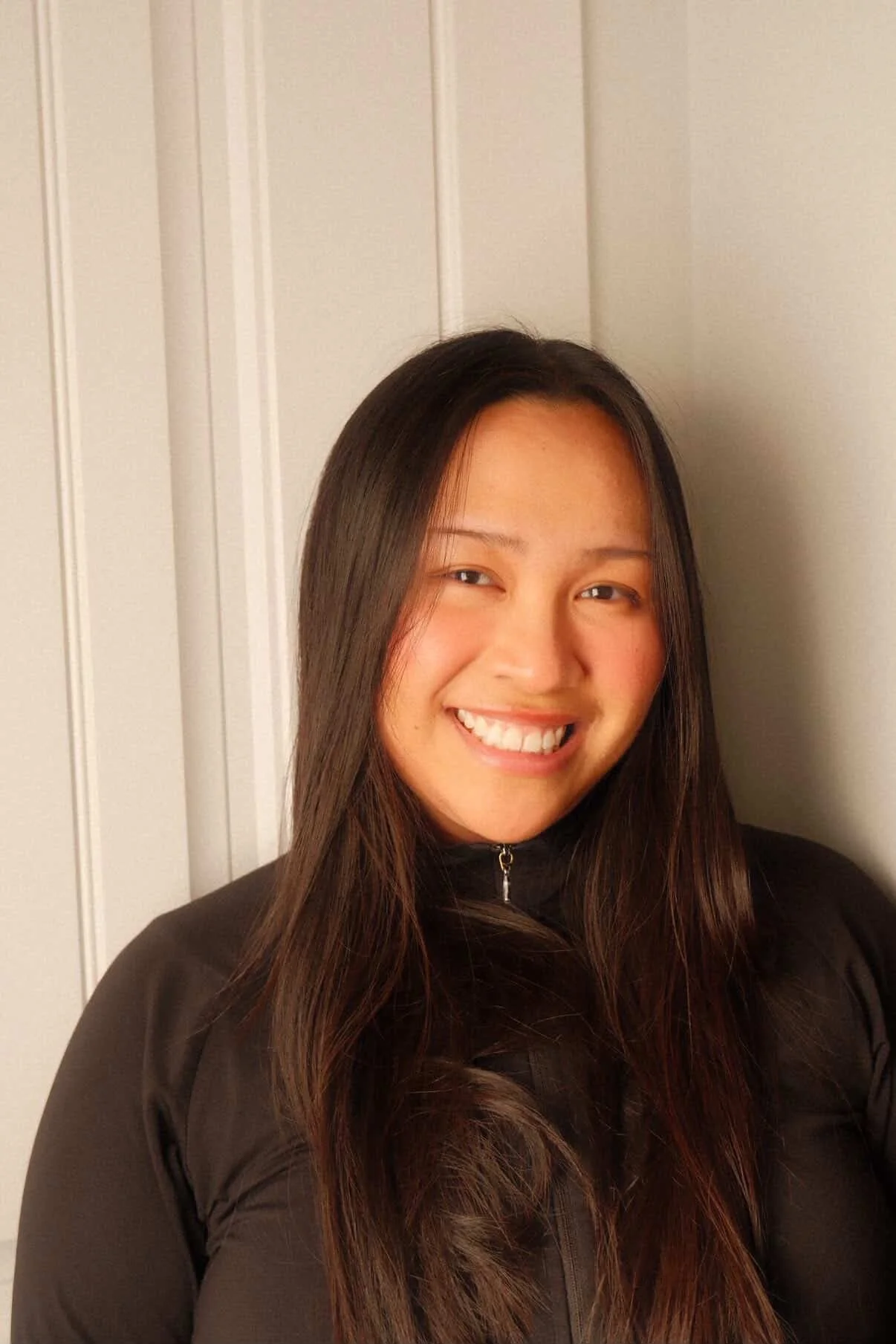 Person wearing a black zip-up sweater standing in front of a white background