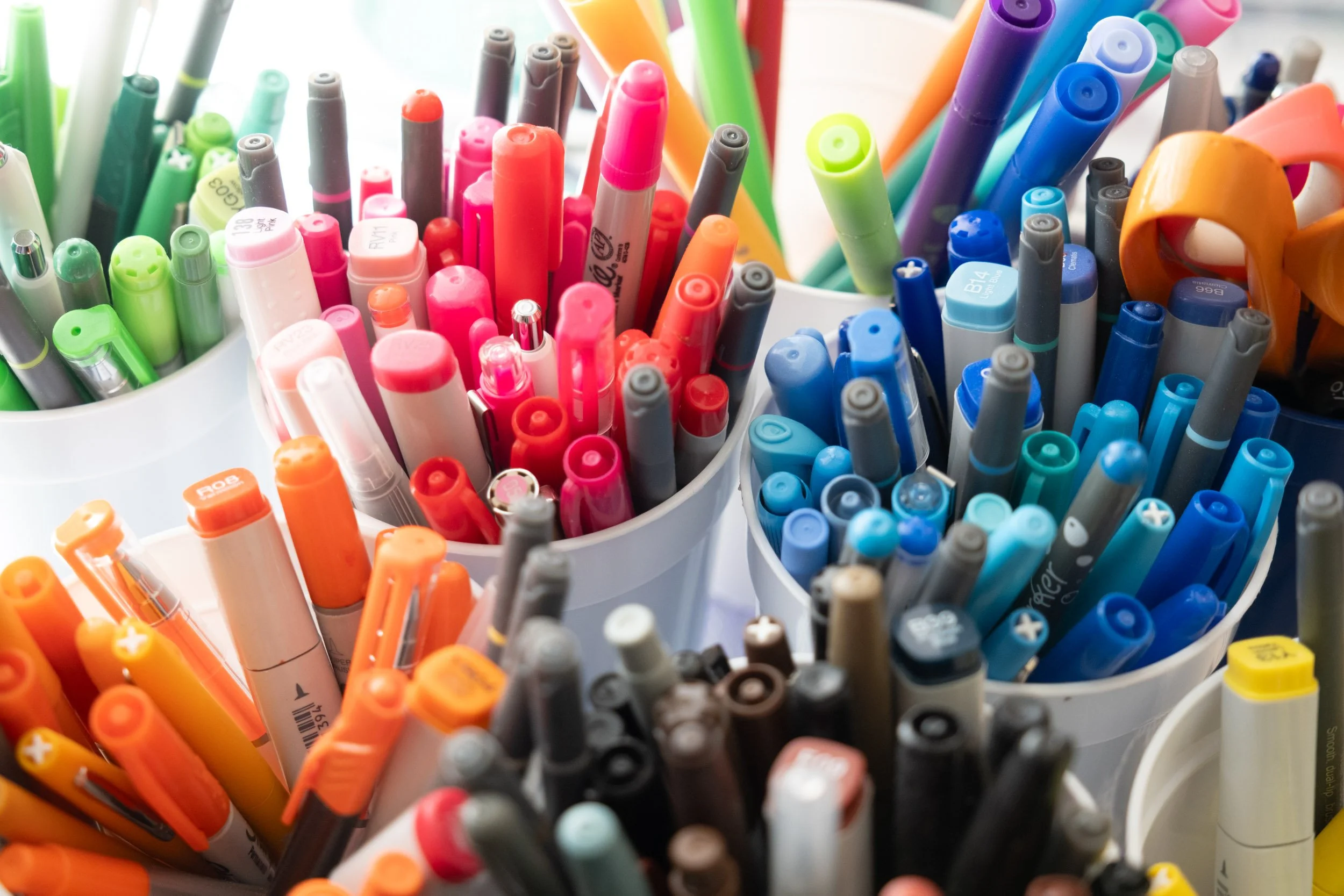 Close-up of colorful markers in white containers.