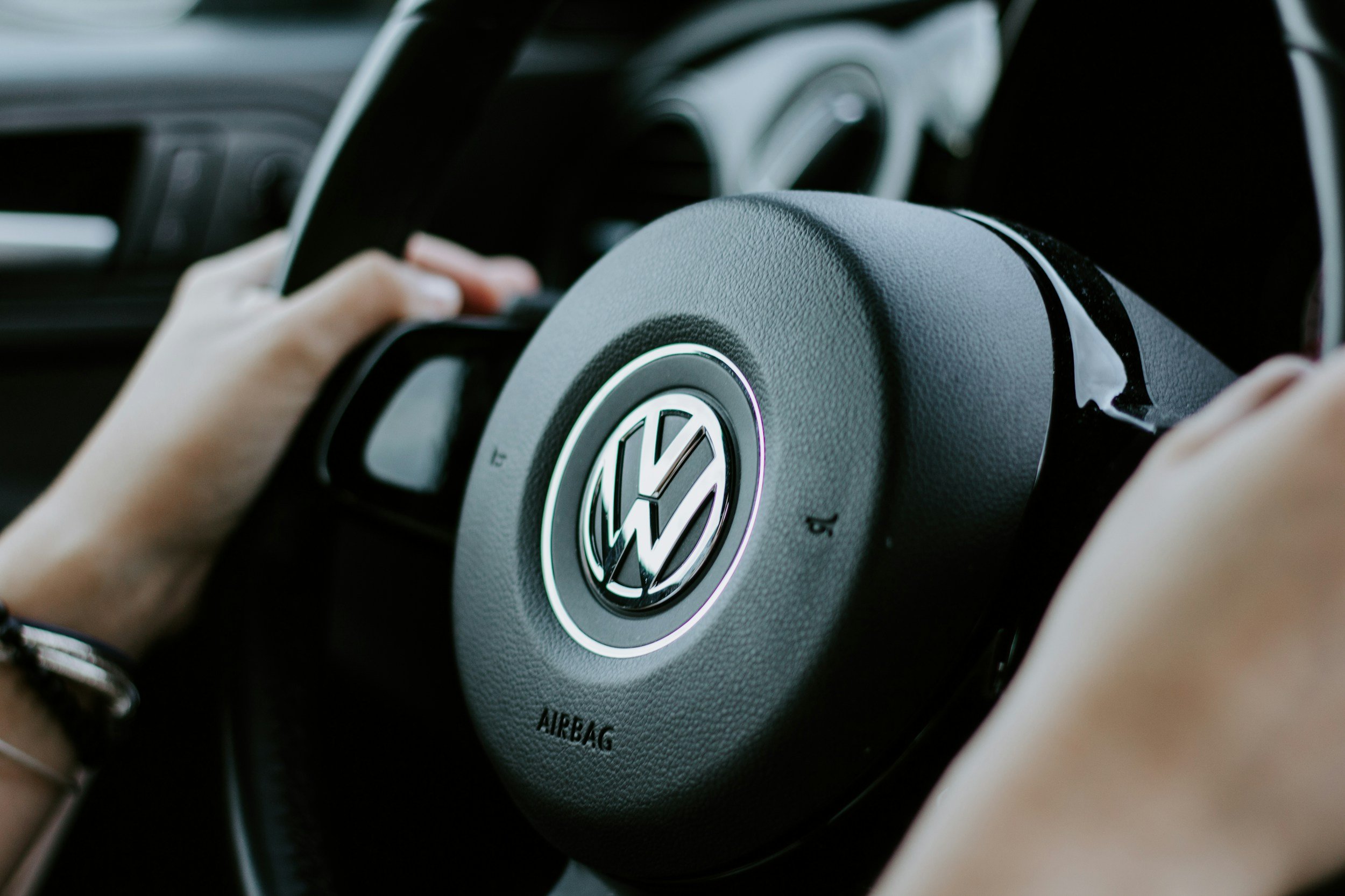 Close-up of a Volkswagen steering wheel, with a person's hands gripping it