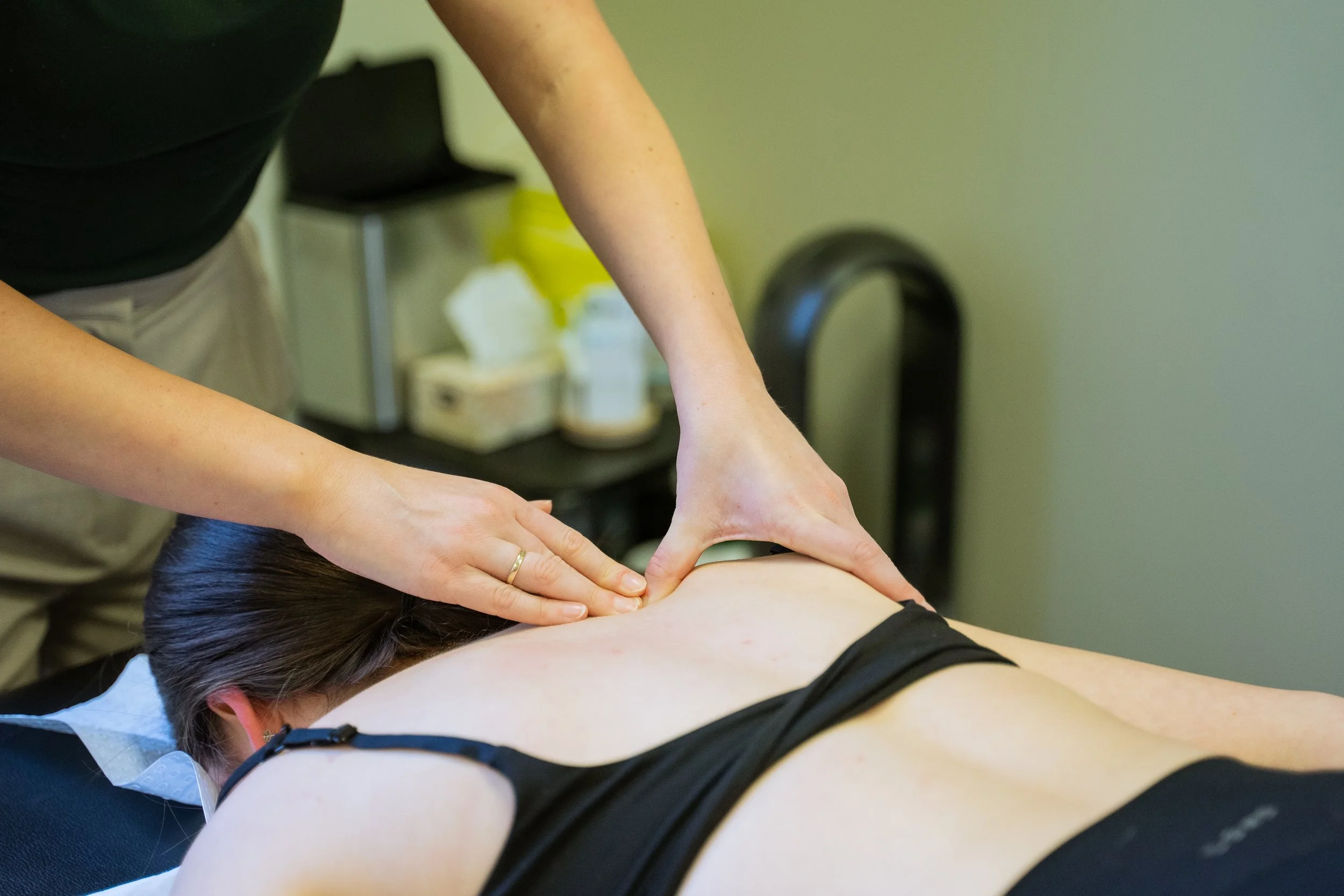 A person receiving a massage on their upper back in a massage therapy setting.
