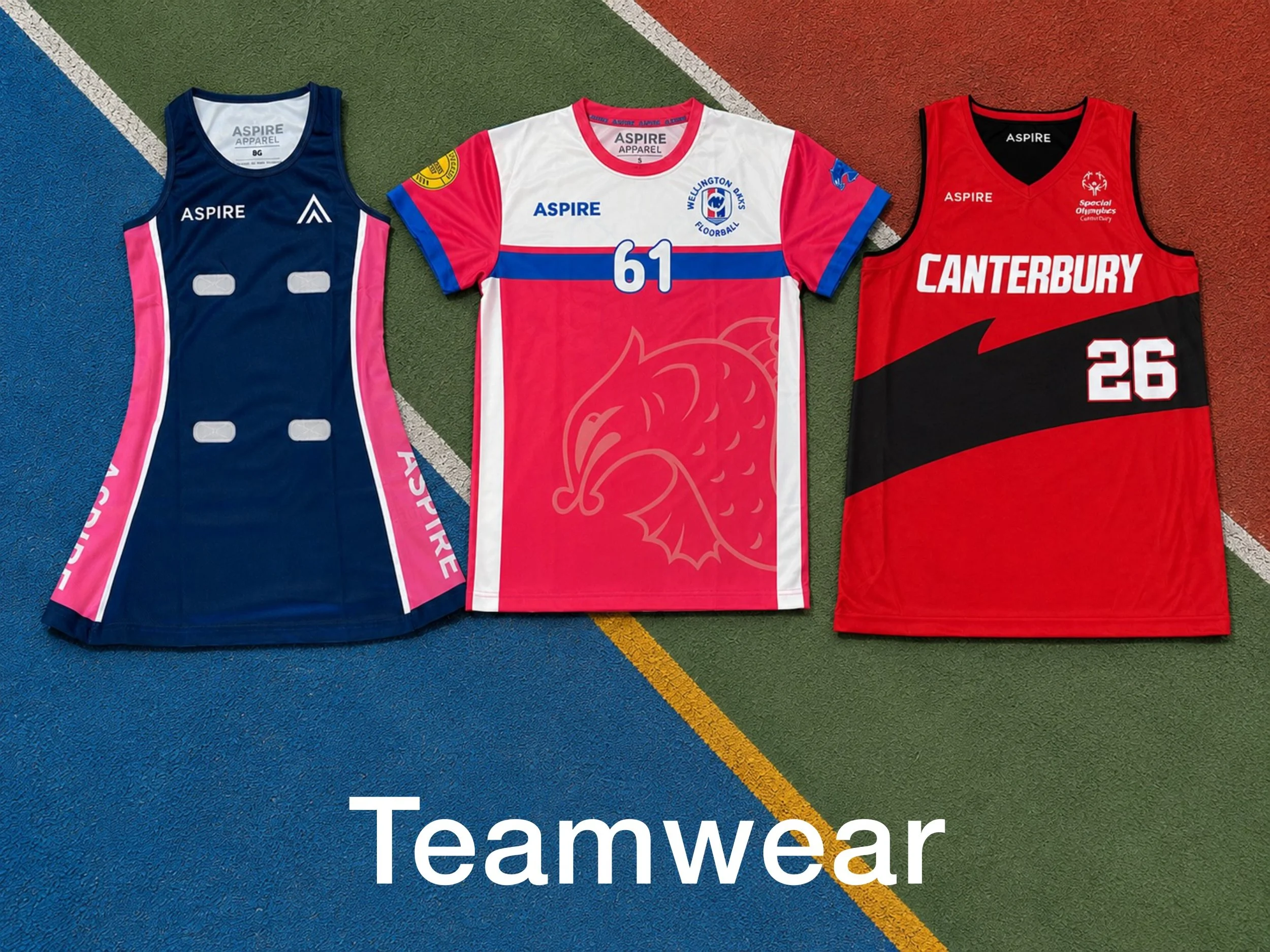 Three Aspire teamwear jerseys displayed on a colorful sports court, including a navy-and-pink singlet, Wellington Parks floorball jersey, and red Canterbury Special Olympics jersey.