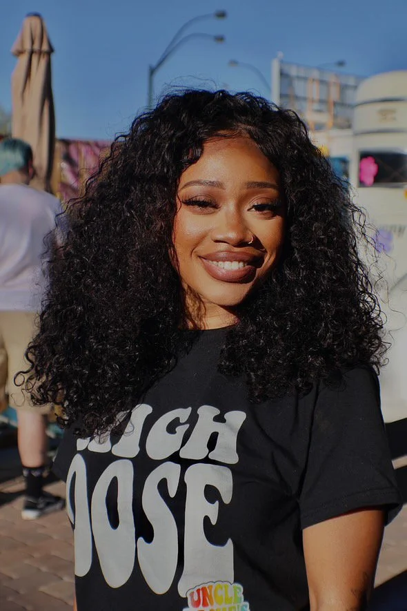 Robyn Williams smiles at the camera in a black tee