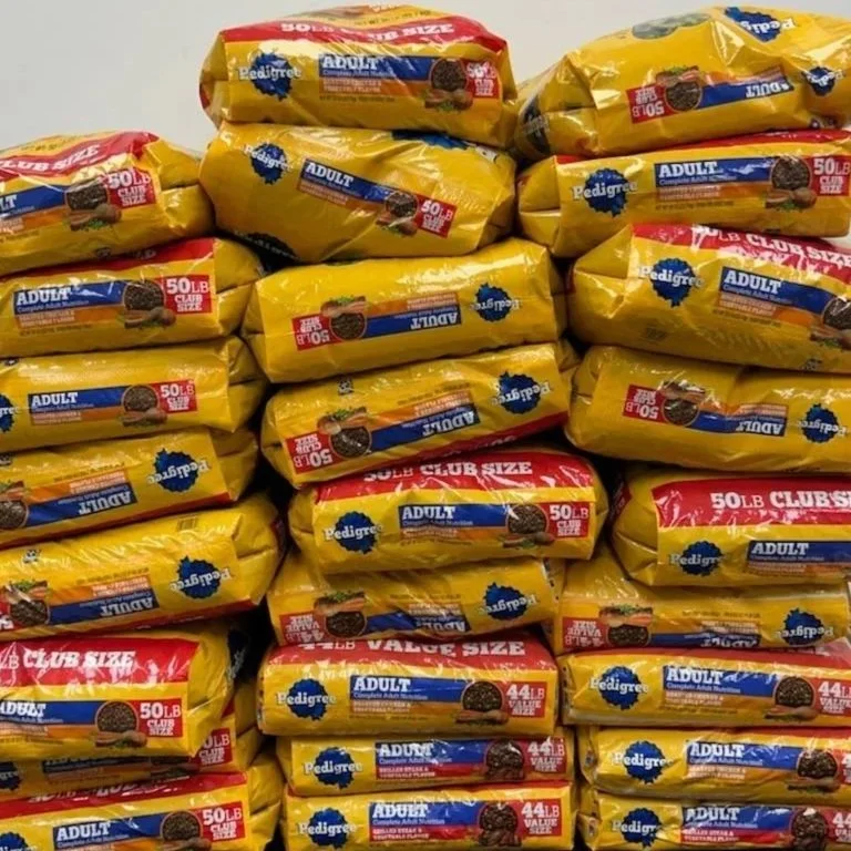 Stacks of Pedigree dog food bags in yellow packaging, with red and blue labels, indicating 50-pound sizes for adult dogs.