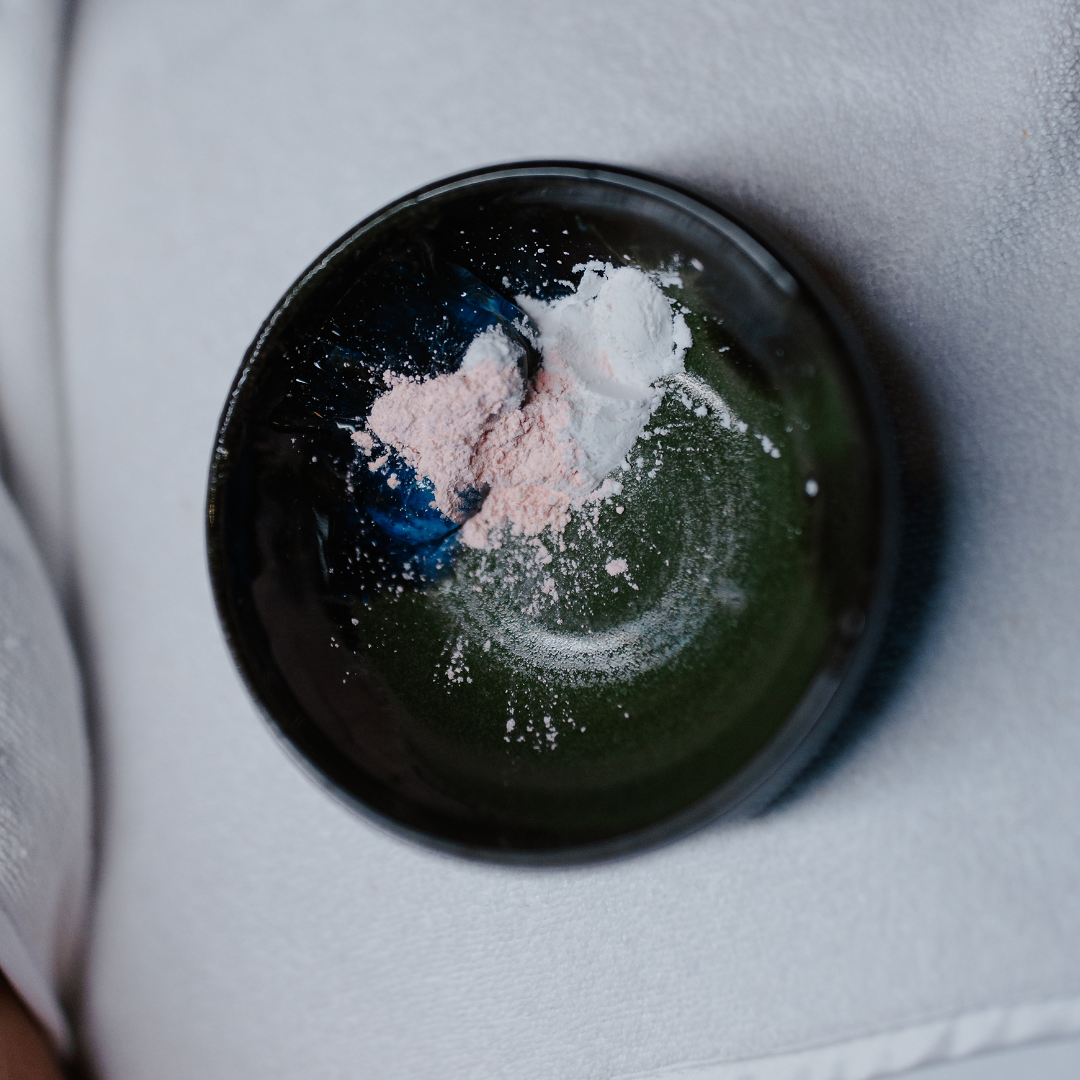 A black container with white and pink powder spilled inside.
