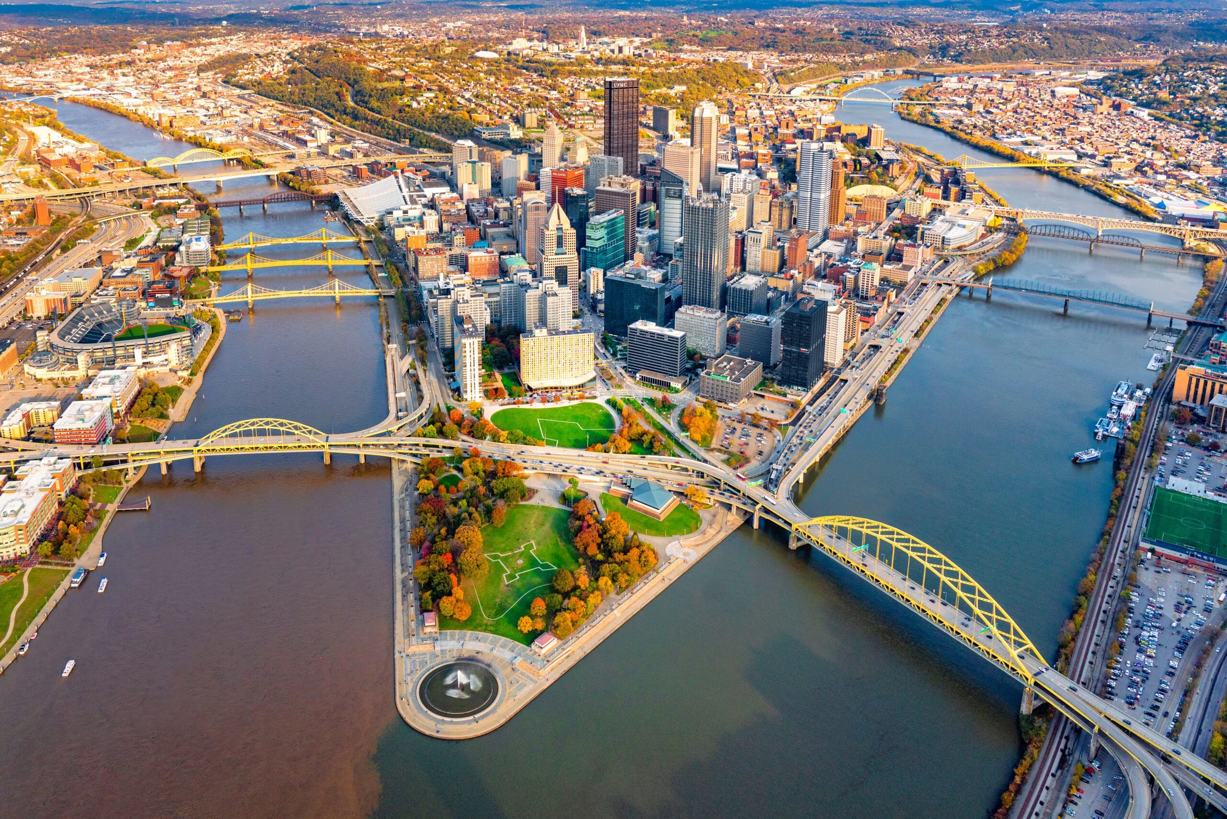Aerial shot of the city of Pittsburgh, displaying the beautiful city skyline and bridges crossing over the rivers.