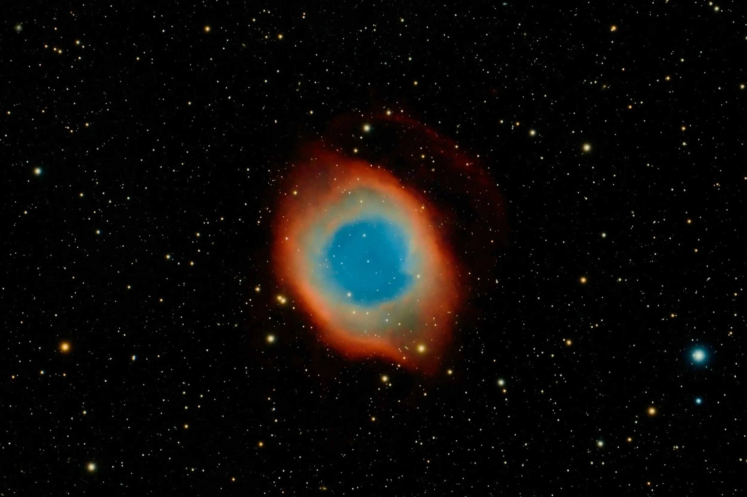 A colorful nebula in space with red, orange, yellow, and blue hues surrounded by numerous stars and cosmic dust.