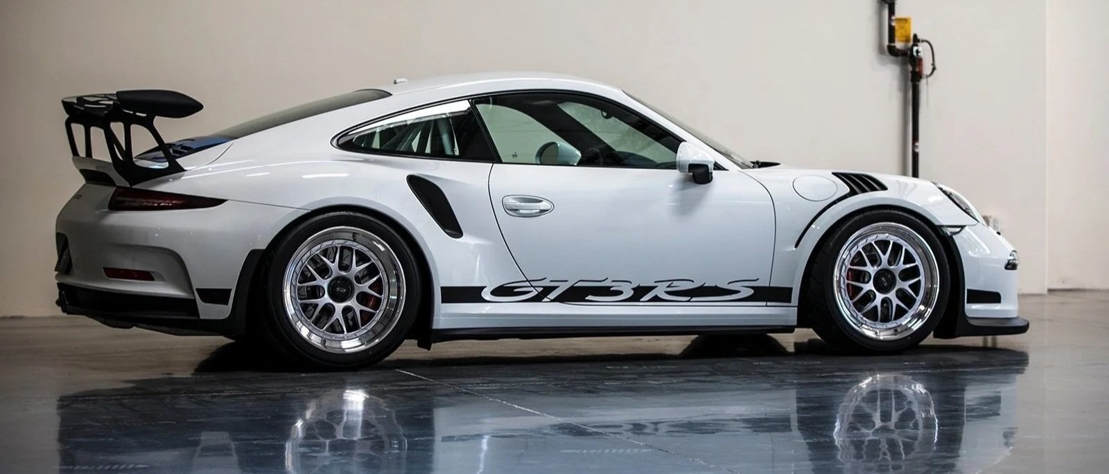 Mirror-finish polished concrete floor reflecting a white sports car in a premium Orange County showroom