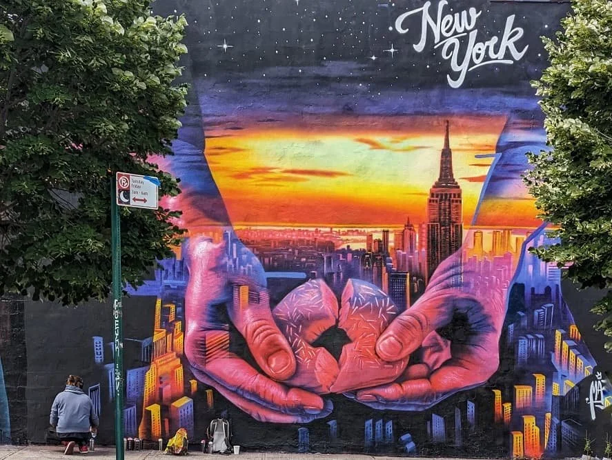 Colorful mural of NYC skyline with Empire State Building and sunset in Bushwick Brooklyn.