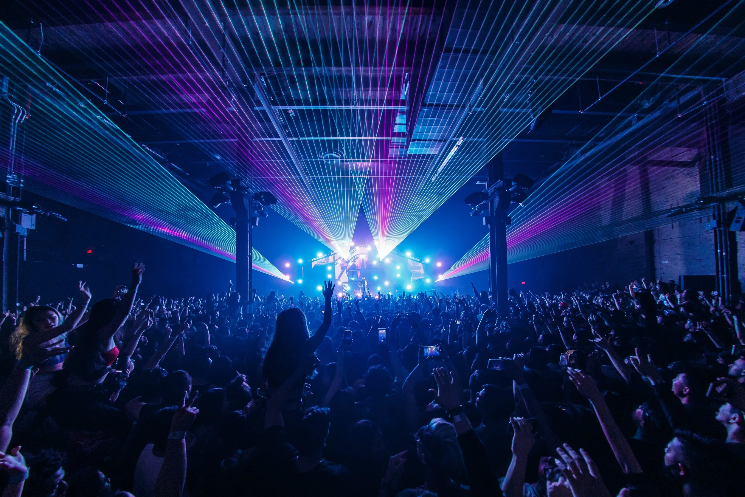 Concert crowd with colorful laser lights at music festival in Brooklyn, New York City.