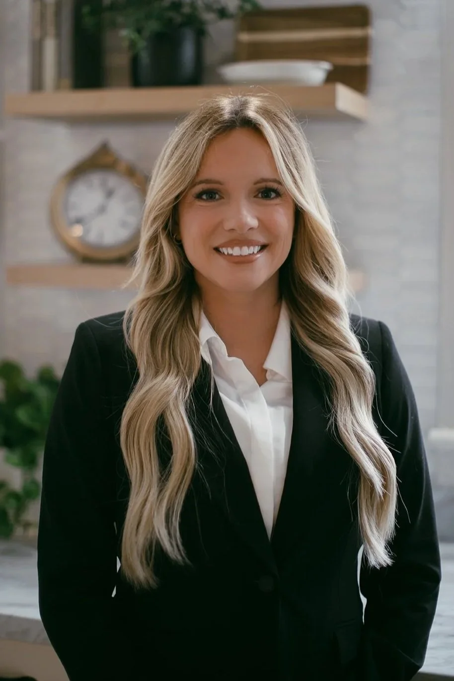 Mountain landscape with rugged rocks in the foreground, misty mountain peaks in the background, and a blue sky with wispy clouds.