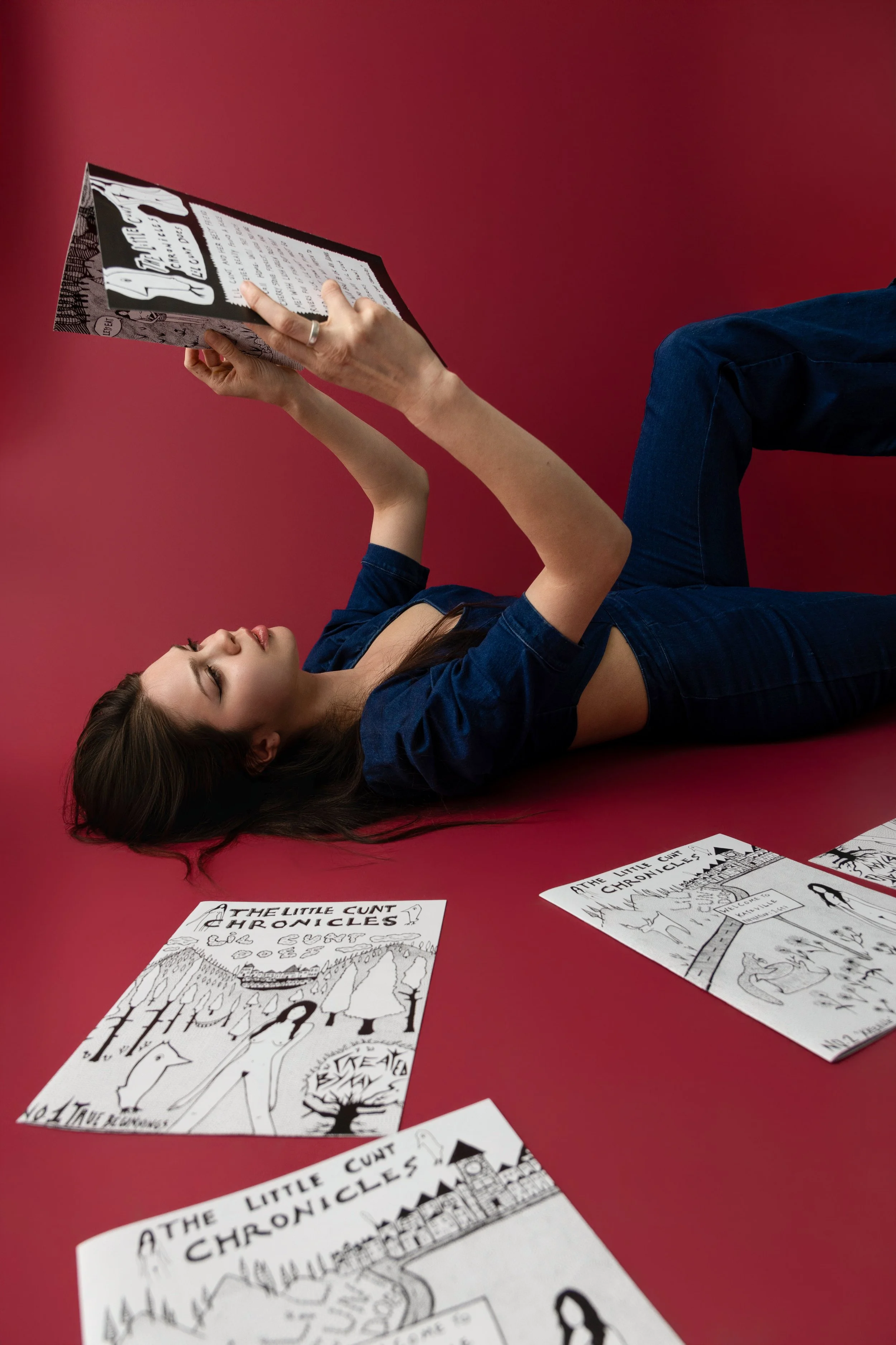 Artist on red backdrop reading her original magazine photographed at No Bounds studio in Denver Colorado