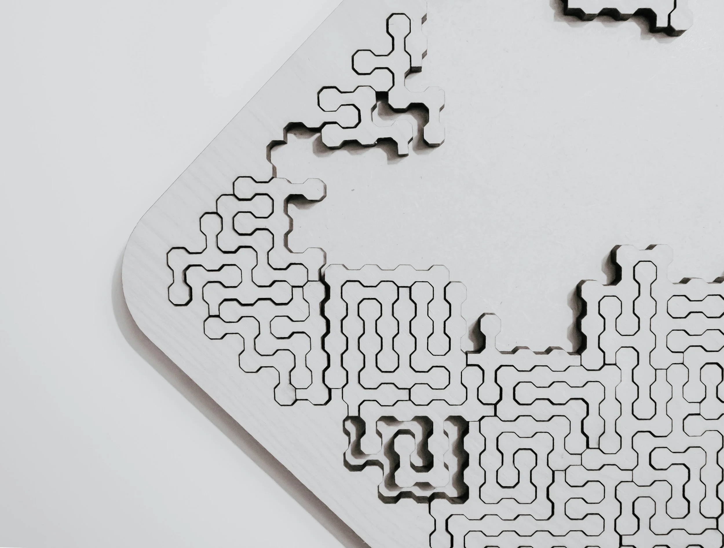 Close-up of a metal maze puzzle with interconnected paths and a textured surface, set against a white background.