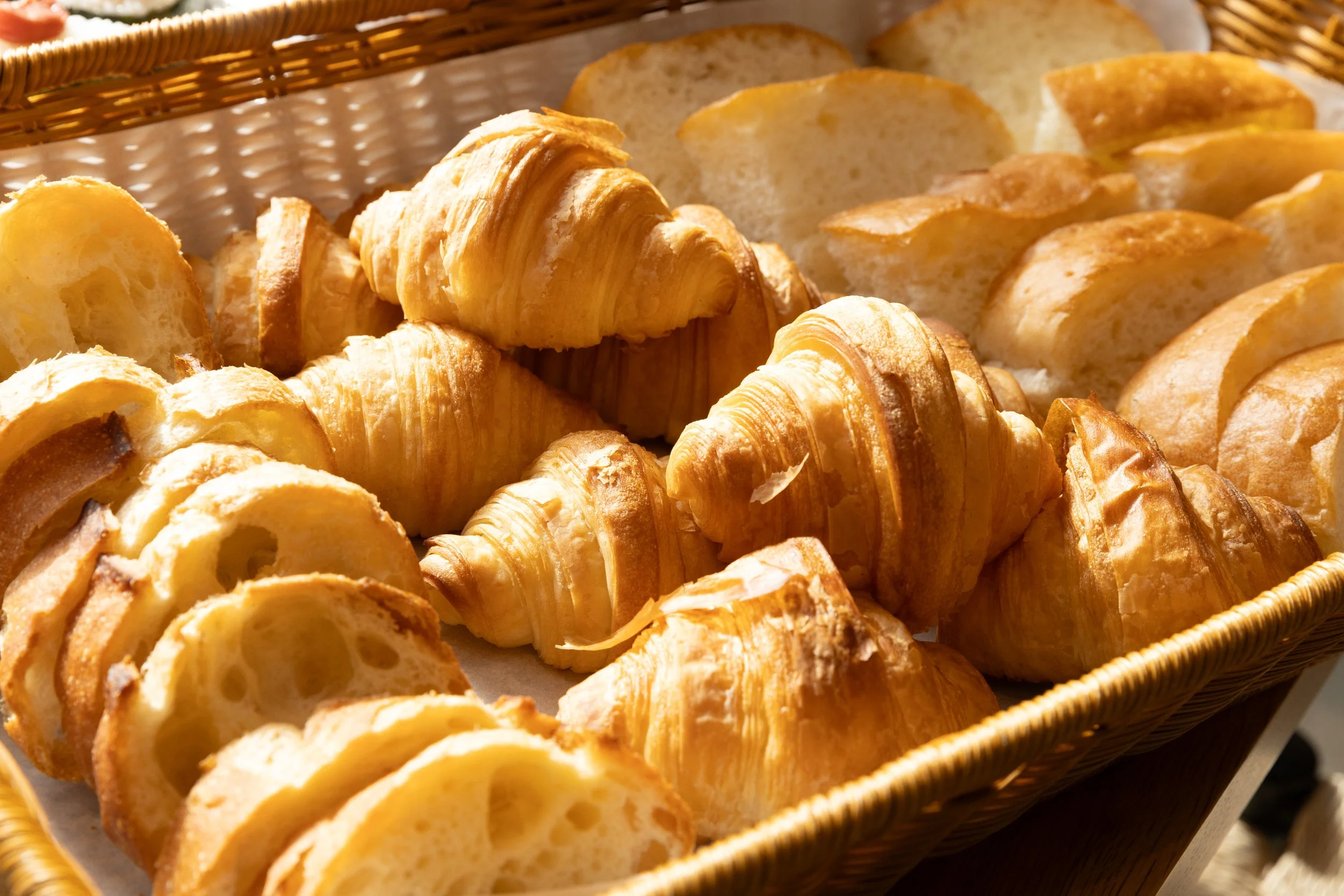 焼きたてのクロワッサンとパンのスライスがバスケットに入っている