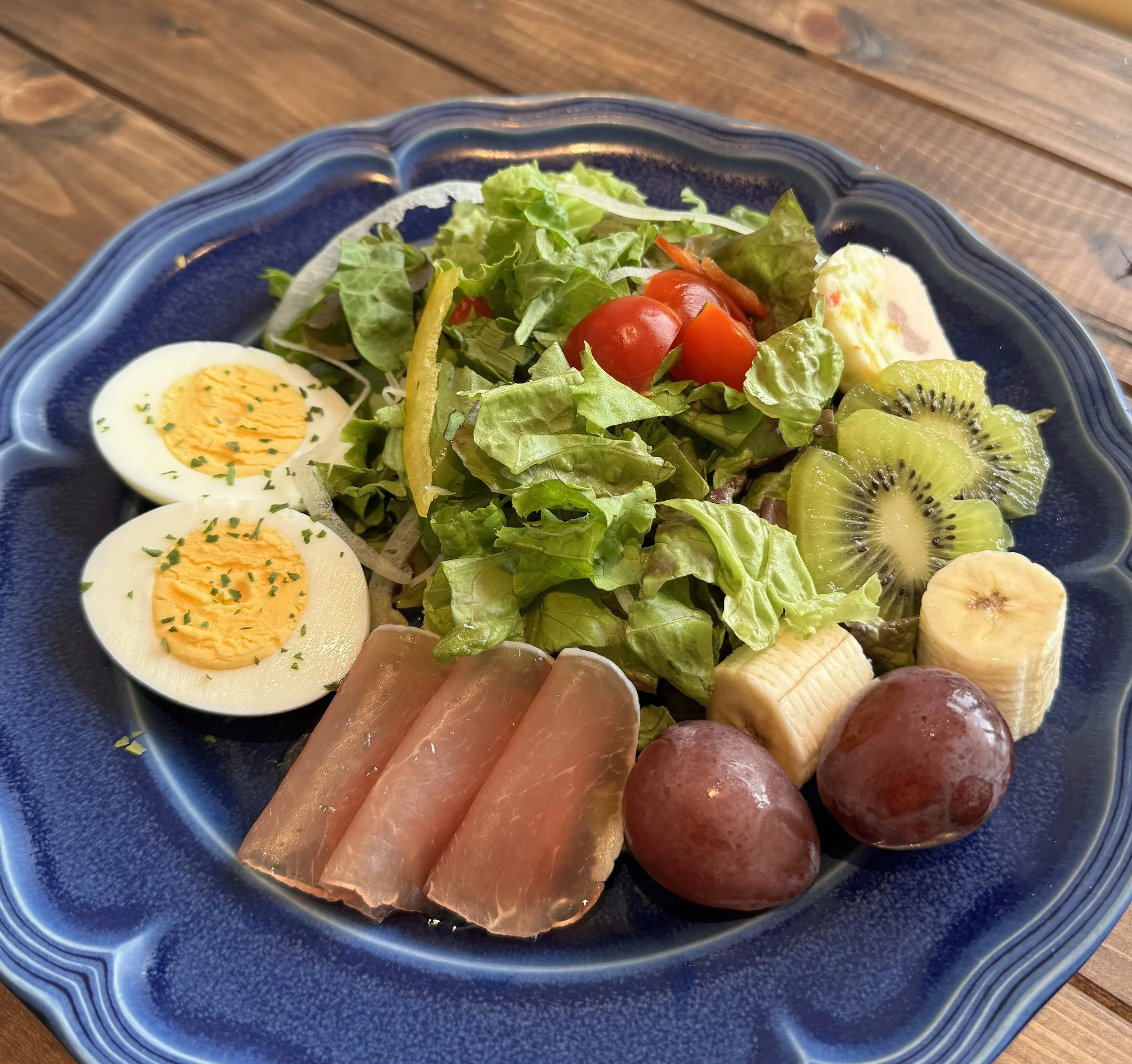 さまざまな野菜と果物、ゆで卵、ハムが盛り付けられたサラダプレート