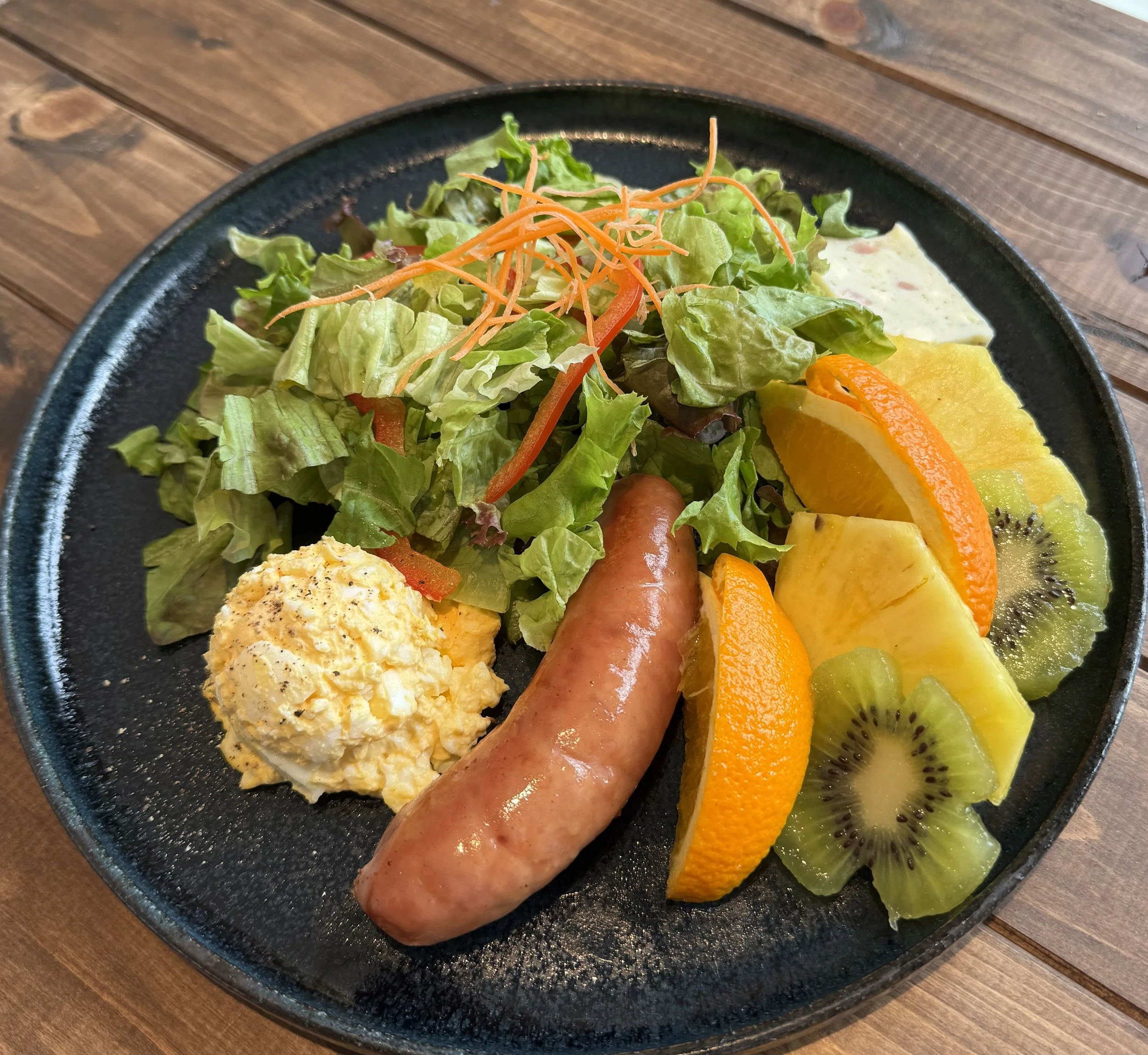 サラダ、フルーツ、ソーセージ、ポテトサラダの盛り合わせたプレート