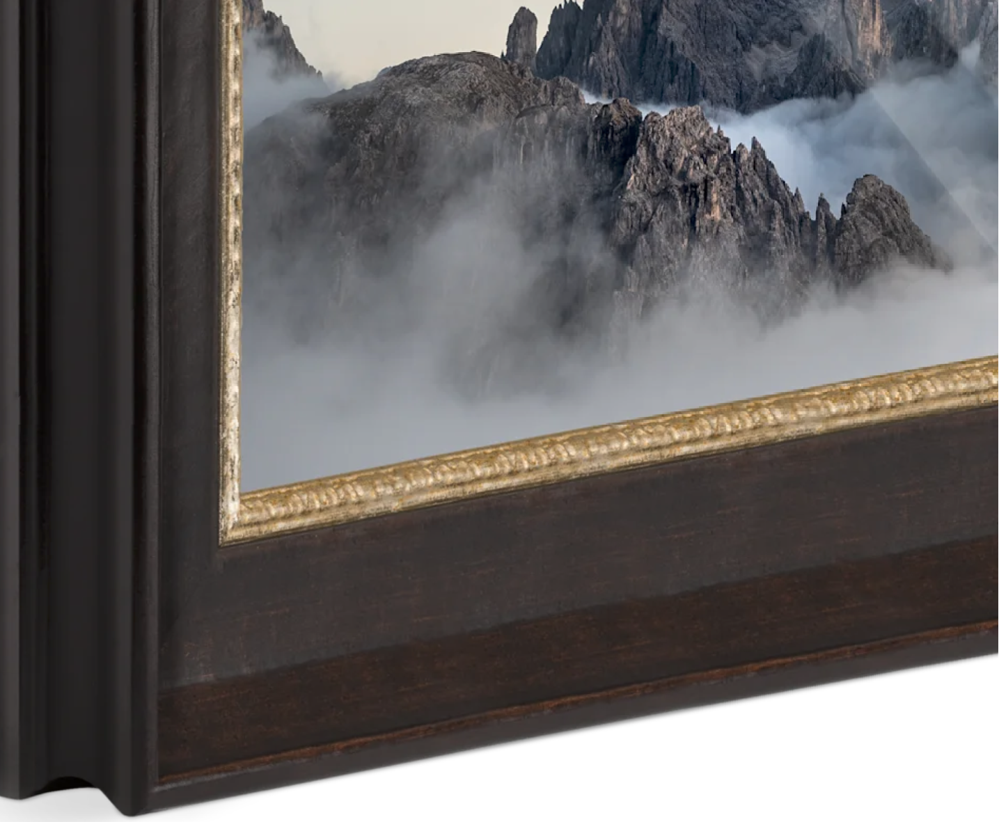 Framed painting of mountains shrouded in clouds, with a dark wood frame and gold decorative trim.