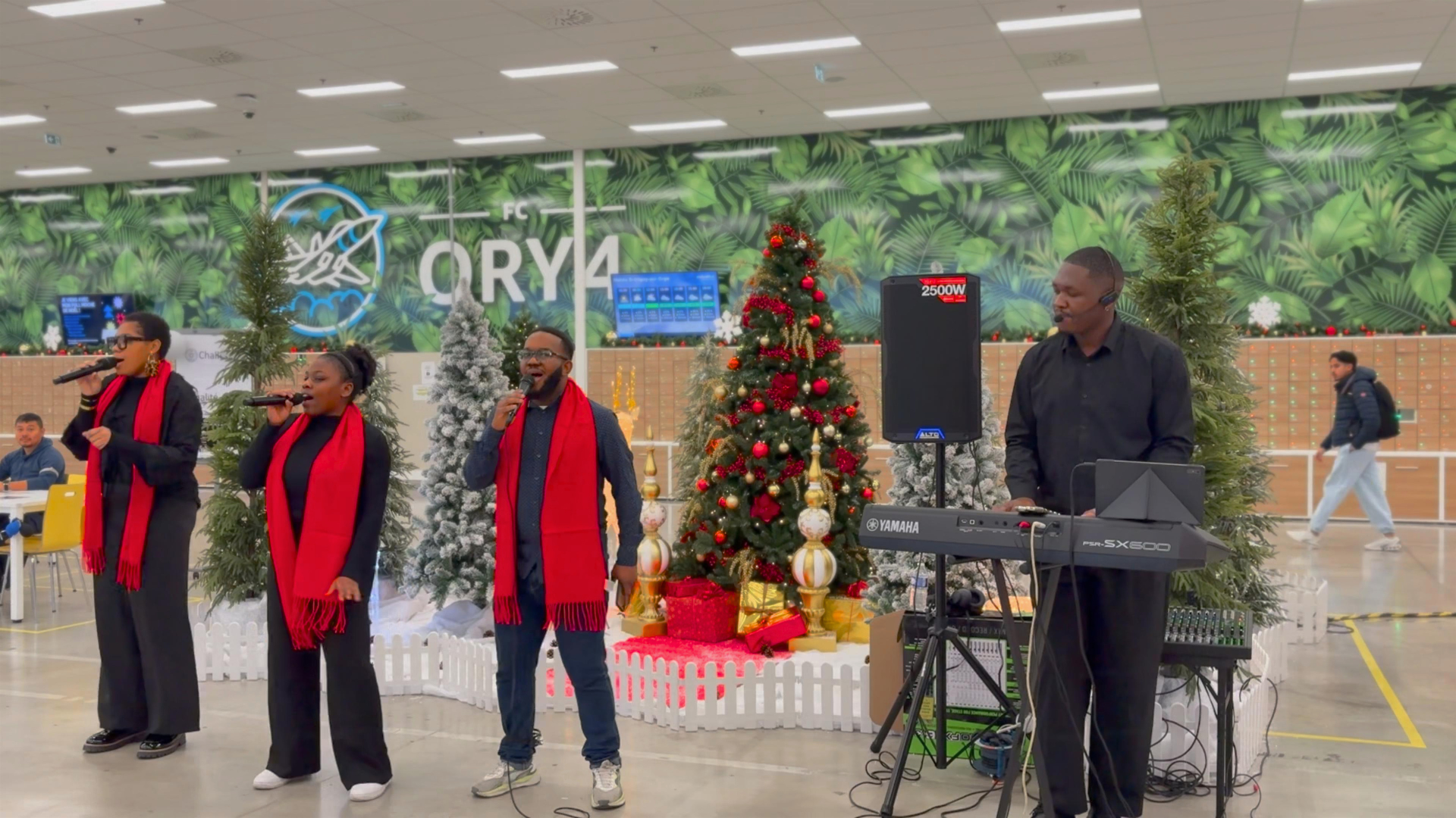 Groupe de chanteurs en ile de france et d'un musicien jouant du clavier dans une décoration de Noël avec arbre et cadeaux dans l'entreprise d'amazoniennes