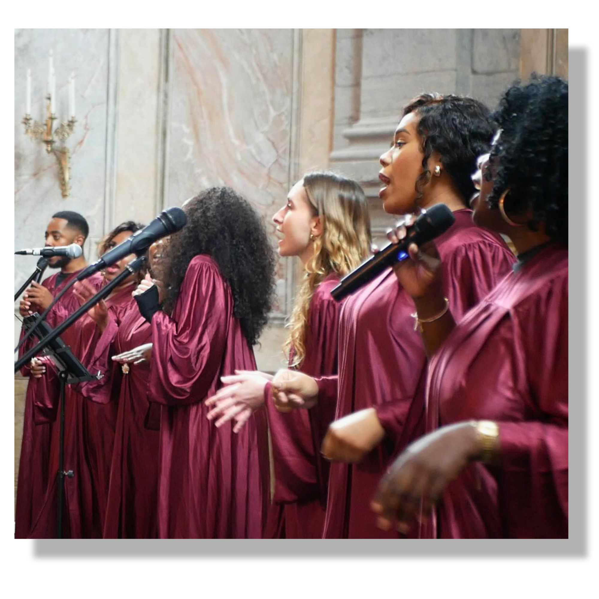 Un groupe de gospel sur paris chante lors d'une cérémonie dans une salle ornée de marbre, vêtues de robes pourpres, avec en arrière-plan des chandeliers en or et un escalier en pierre.