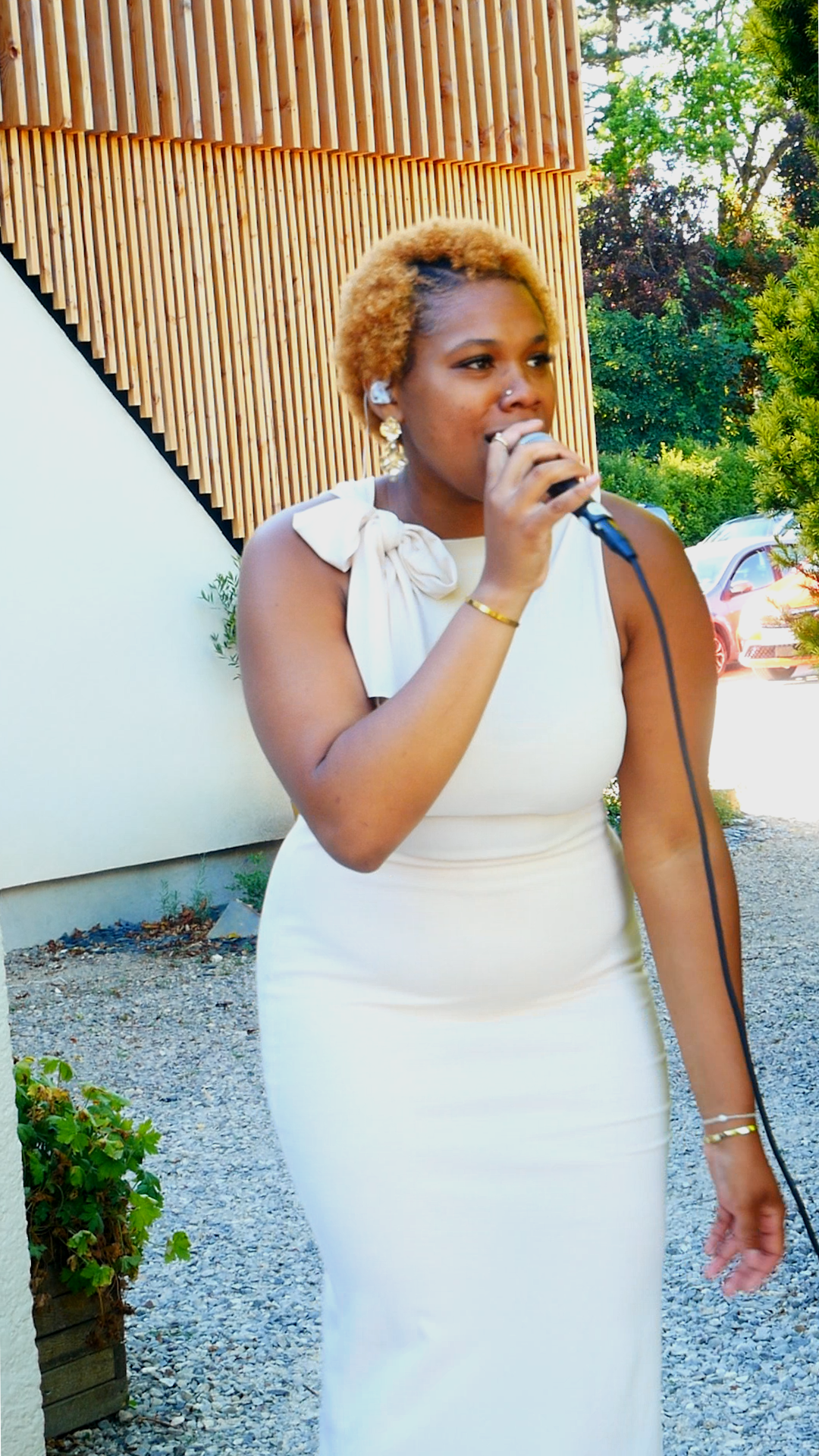 Une femme portant une robe blanche, parlant ou chantant dans un micro lors d'un mariage en haut-de-france