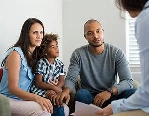A family of three sitting on a couch during a parental counseling session, talking to a counselor.