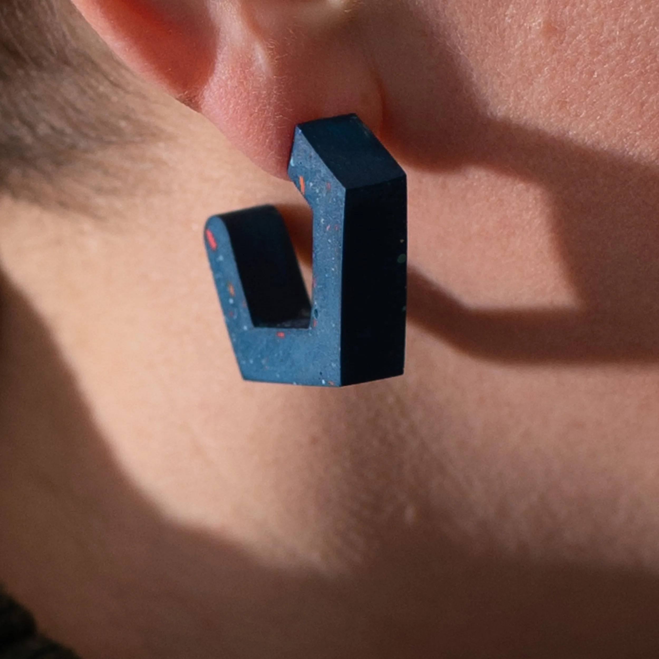 model wears a chunky blue jesmonite earring showing terrazzo finish to reverse