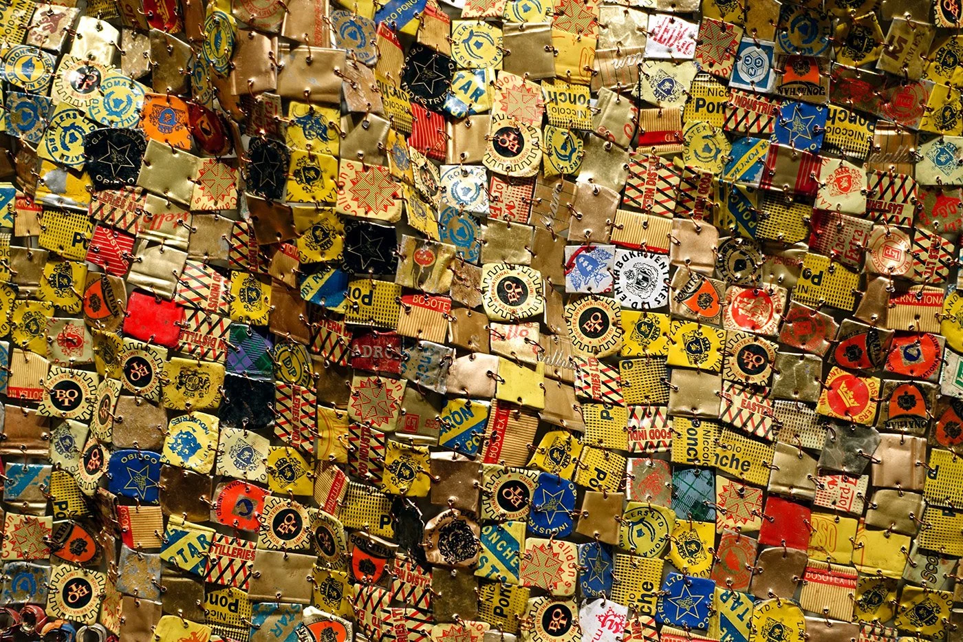 Close-up of an El Anatsui tapestry of flattened bottle caps in yellow, red and blue
