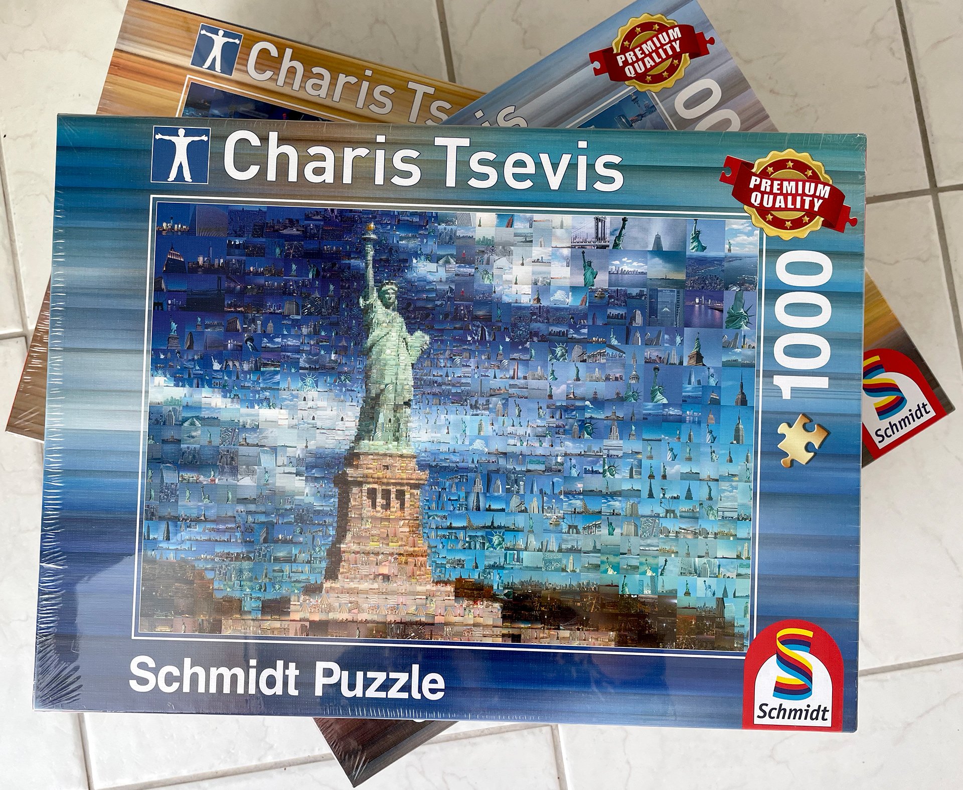  Boxed 1000-piece Schmidt puzzle showing a mosaic of the Statue of Liberty, stacked on other puzzle boxes 