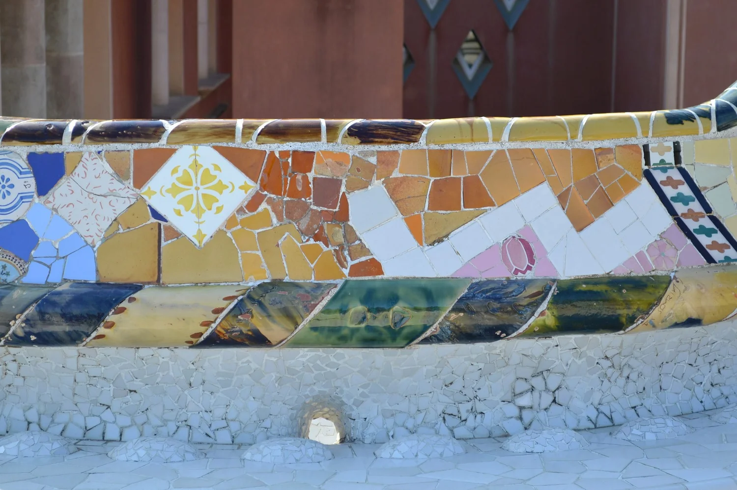 Curved bench surface covered in broken coloured ceramic tiles of many patterns