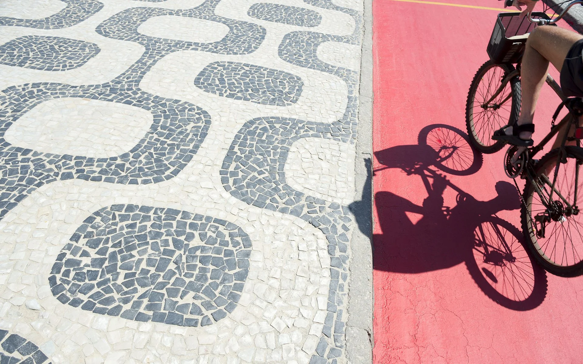 Close-up of Portuguese-style stone mosaic pavement in Copacabana, showing undulating black-and-white wave patterns made from basalt and limestone.