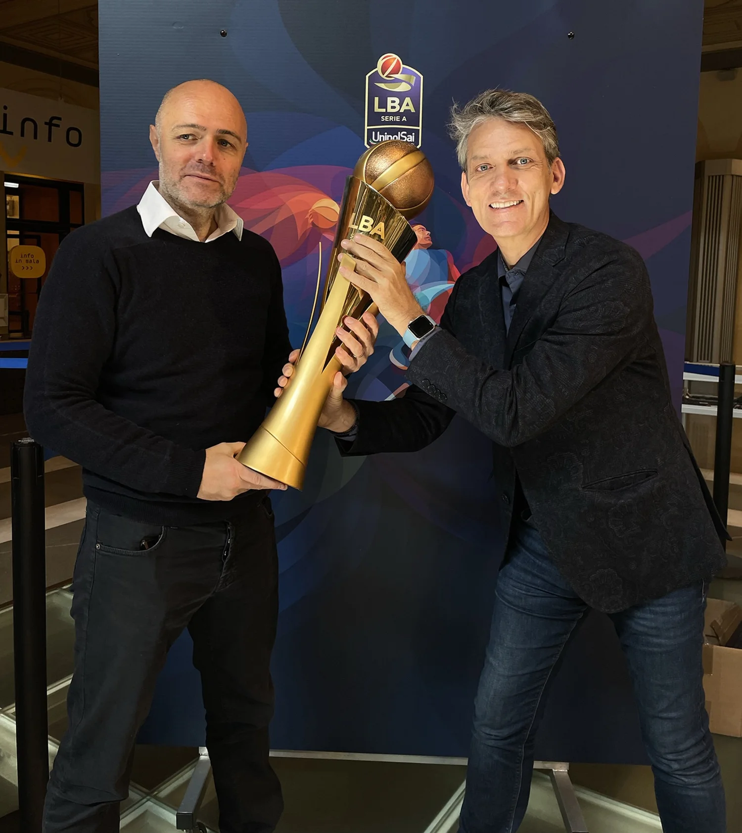 Paolo Guidobono, creative director of Foolbite, and Charis Tsevis pose with a golden trophy at the presentation of the Lega Basket Serie A season 2023-2024 in Bologna.