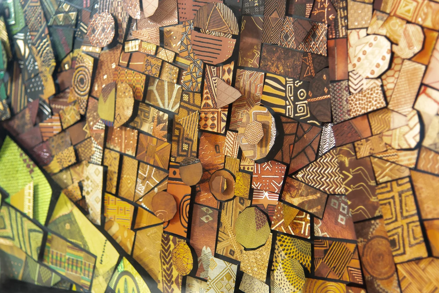 Close detail of a paper mosaic with small cut tiles in orange, green and brown geometric patterns, some of them round