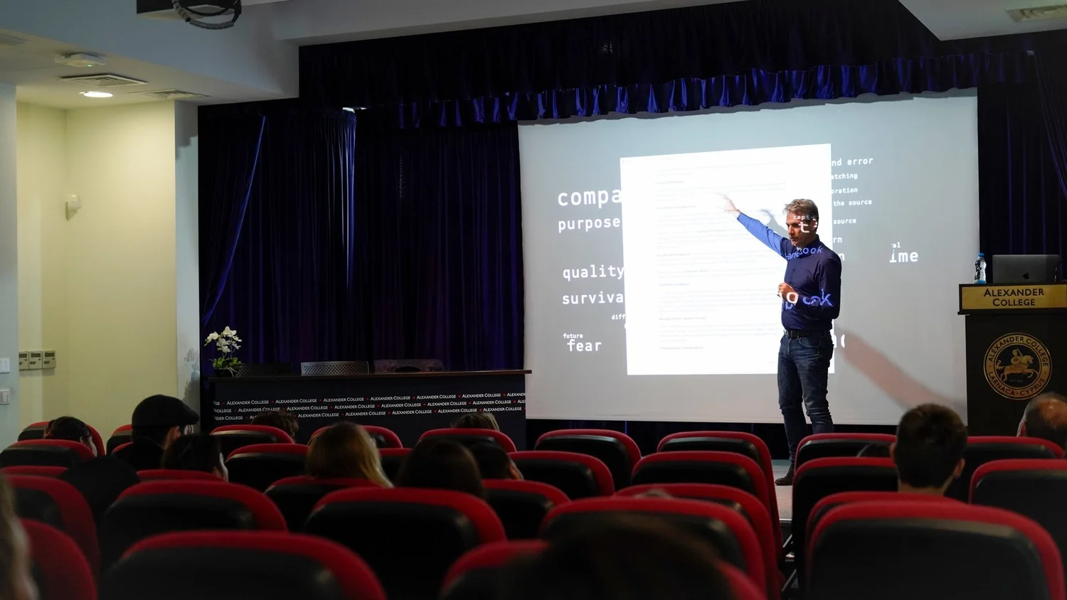 Charis Tsevis pointing at a slide with the words compass, purpose and fear, in front of a seated audience