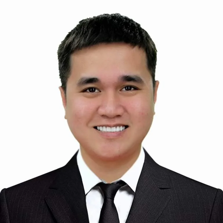 A woman with curly hair and glasses smiling in an indoor setting.