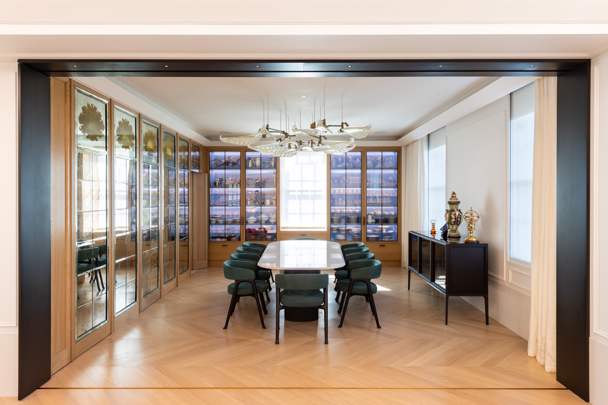 Elegant dining room with a large oval table surrounded by green chairs. 