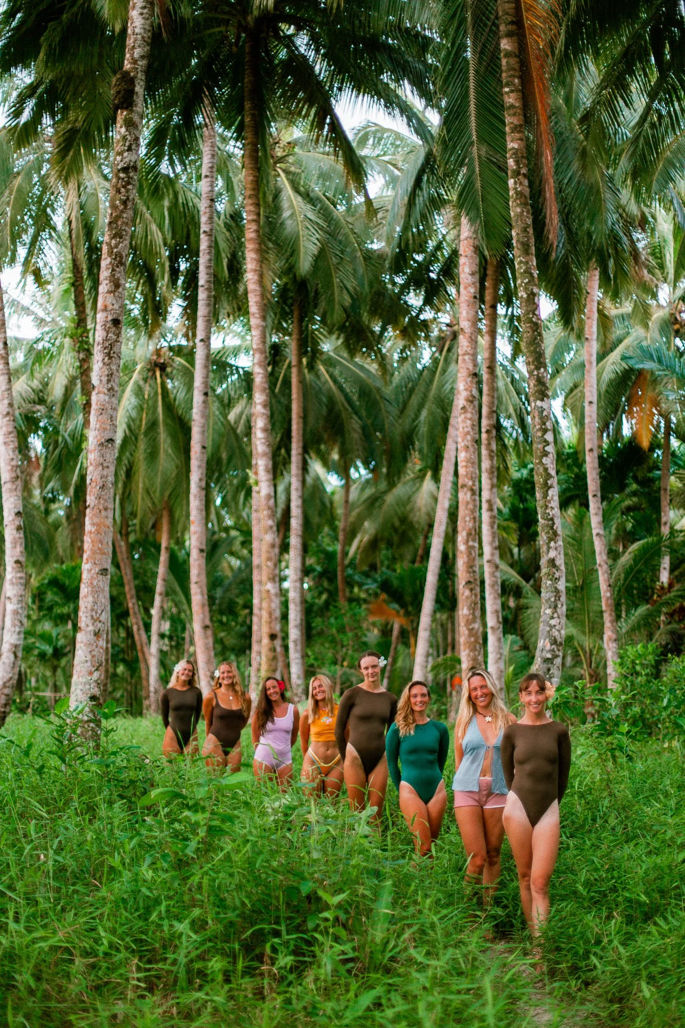 A group of women walking in a lush tropical forest with tall palm trees.