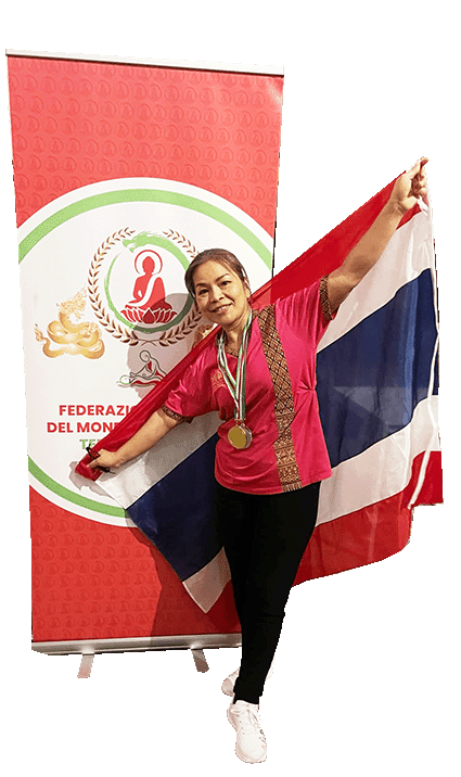 Masseurin Yanisa Borys mit Goldmedaille, hält eine thailändische Flagge, steht vor einem roten Banner einer Massage Weltmeisterschaft.