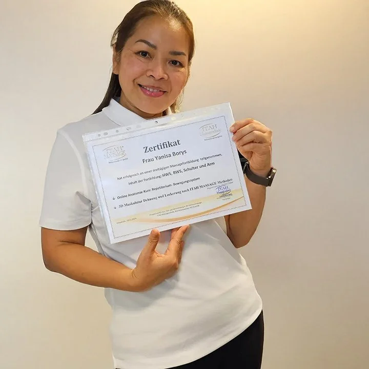 Yanisa Borys zeigt ein Massage-Zertifikat mit der Weiterbildung im ISG-Bereich.