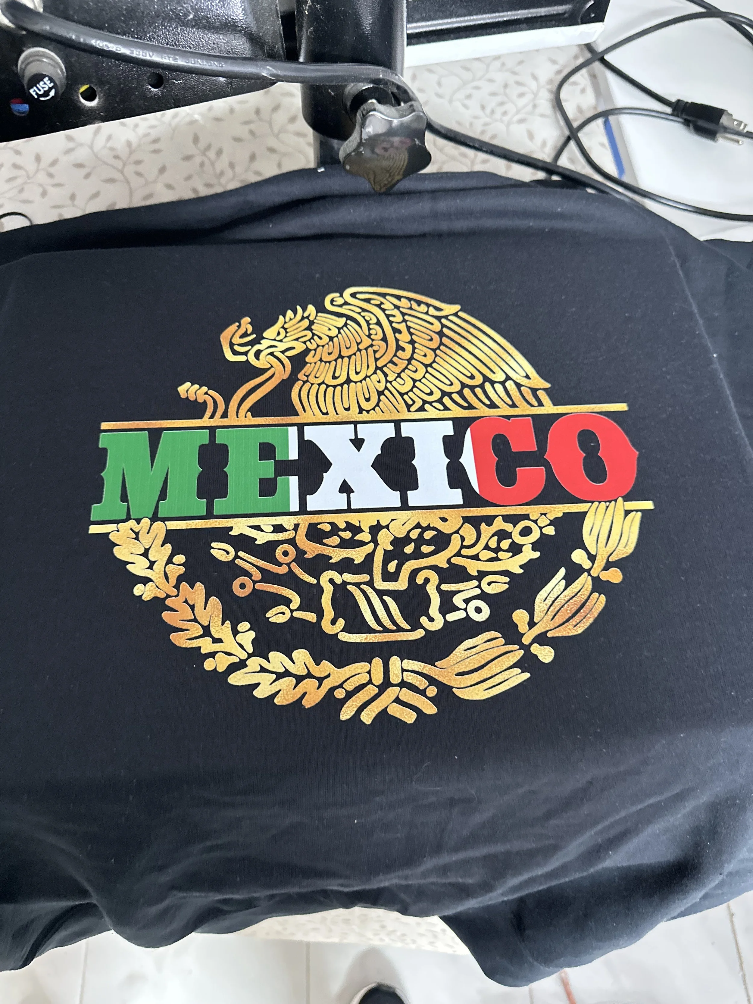 Black T-shirt with a colorful Mexico-themed design and the word 'MEXICO' in green, white, and red letters, featuring a stylized eagle and laurel wreath.