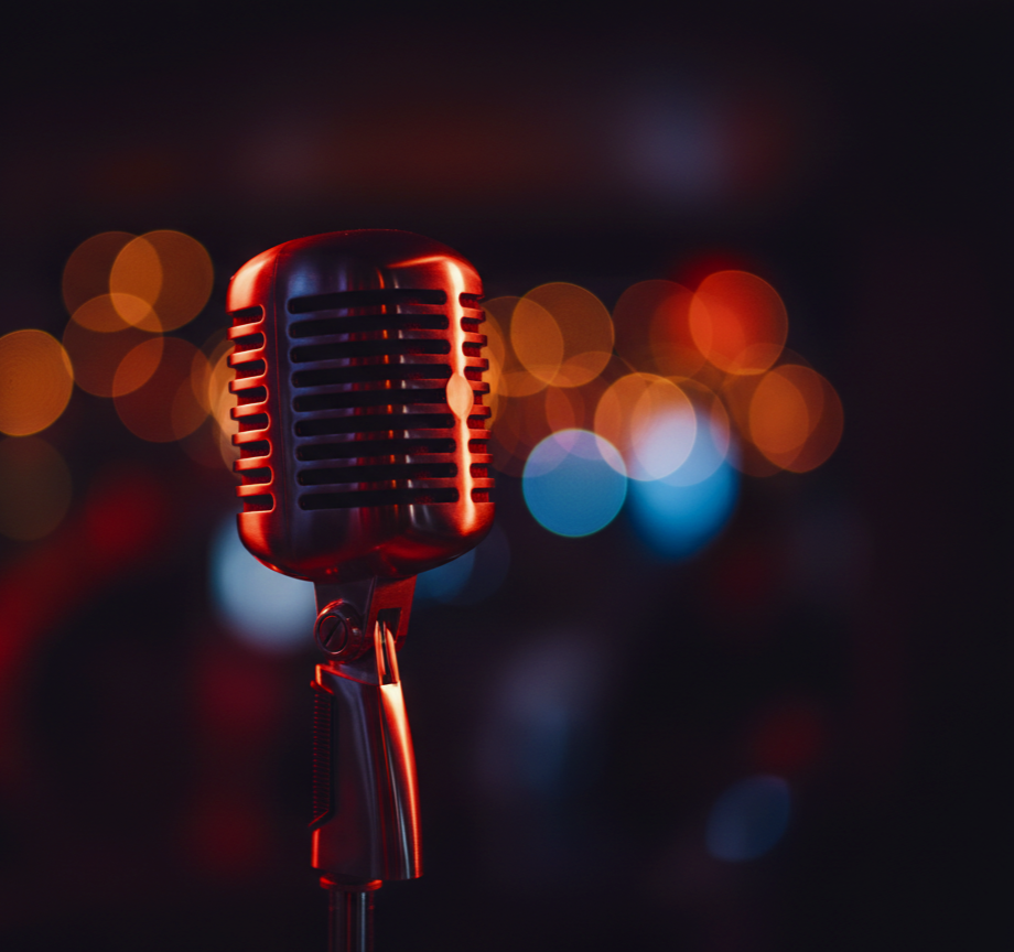Close-up of a vintage red microphone with blurred colorful city lights in the background.