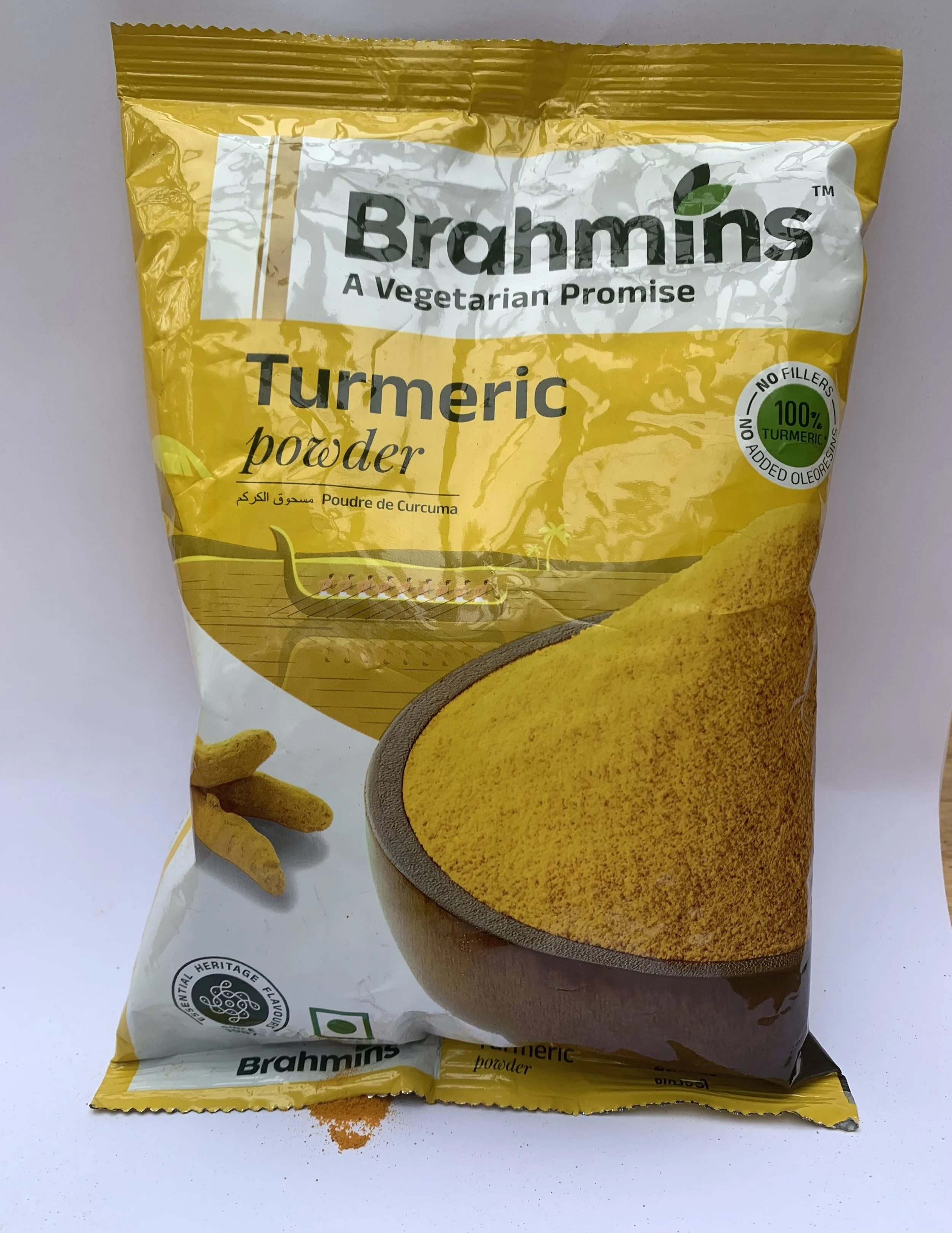 Package of Brahmins turmeric powder with spilled spice residue beneath the packaging, referencing caste, purity, branding, and consumption.