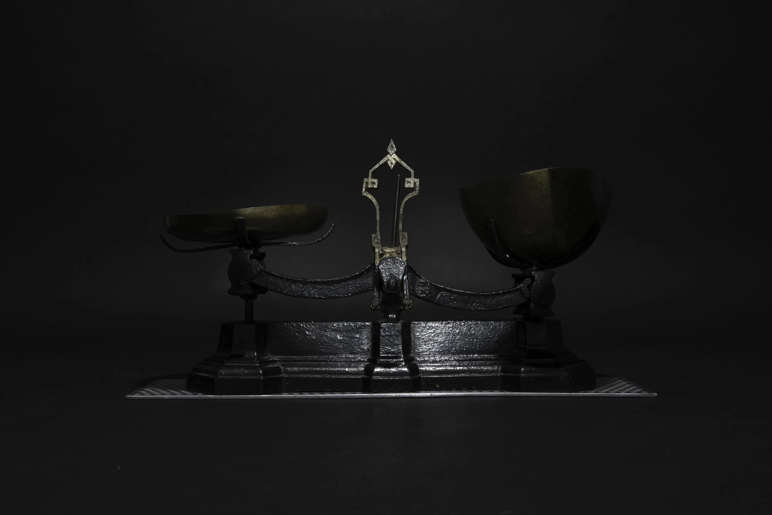 18/13 (2026), conceptual structure by Ugandan-American artist Jonah Batambuze, examining racial representation in colonial Kampala through a cast-iron balance scale and engraved brass identification tags.